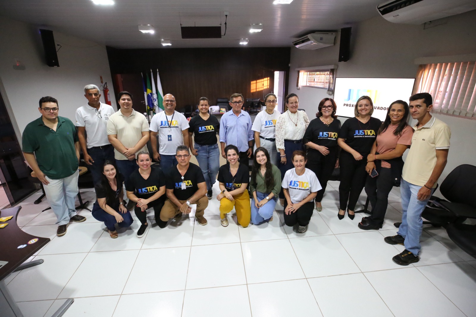 foto colorida horizontal mostra servidores e servidoras do forum do forum de itacaja e do tjto junto a presidente do tribunal no salão do juri