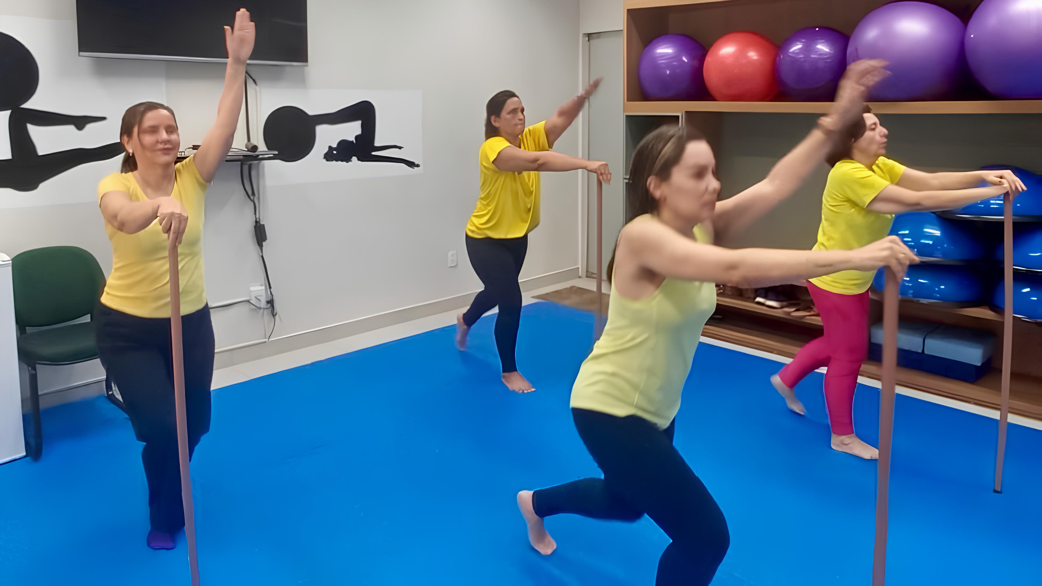 foto colorida horizontal revela quatro mulheres vestindo camiseta amarela em durante uma aula prática de mat pilates