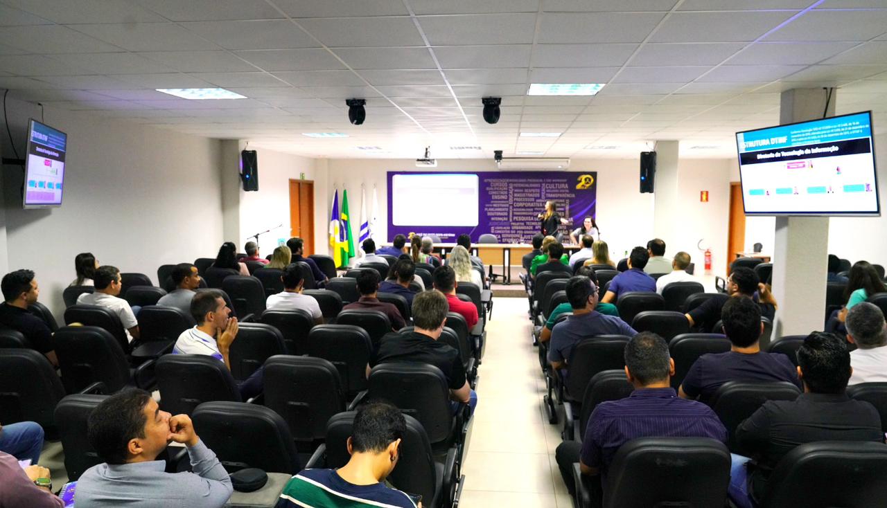 Sala com vários servidores da Dtinf sentados; ao fundo a diretora em pé falando 