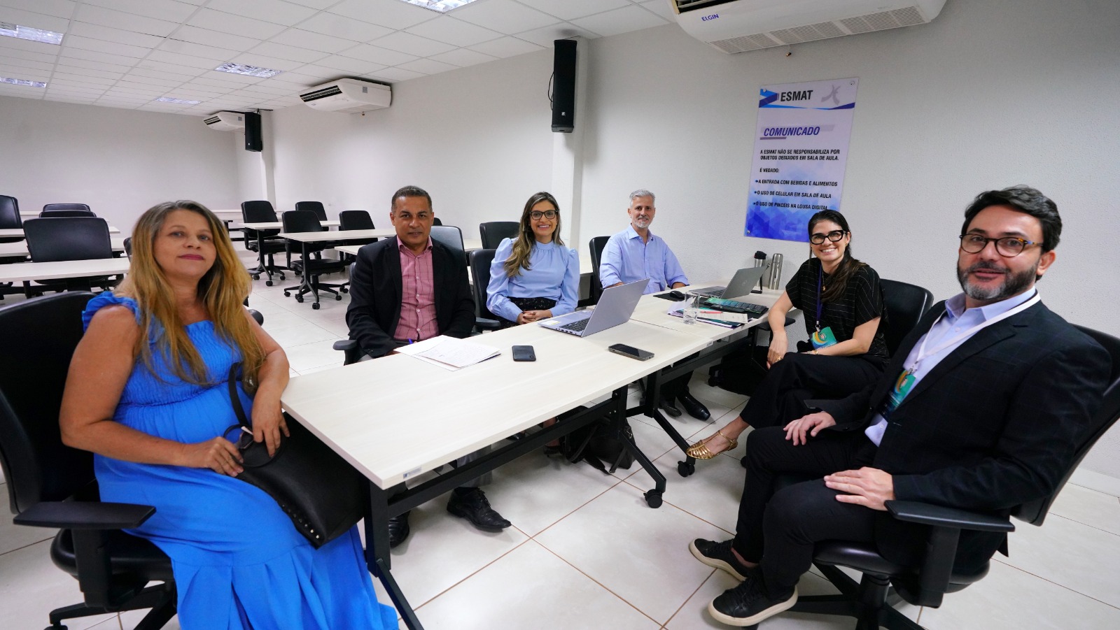 Fotografia colorida que mostra três homens e três mulheres sentados em volta de uma mesa, debatendo temas