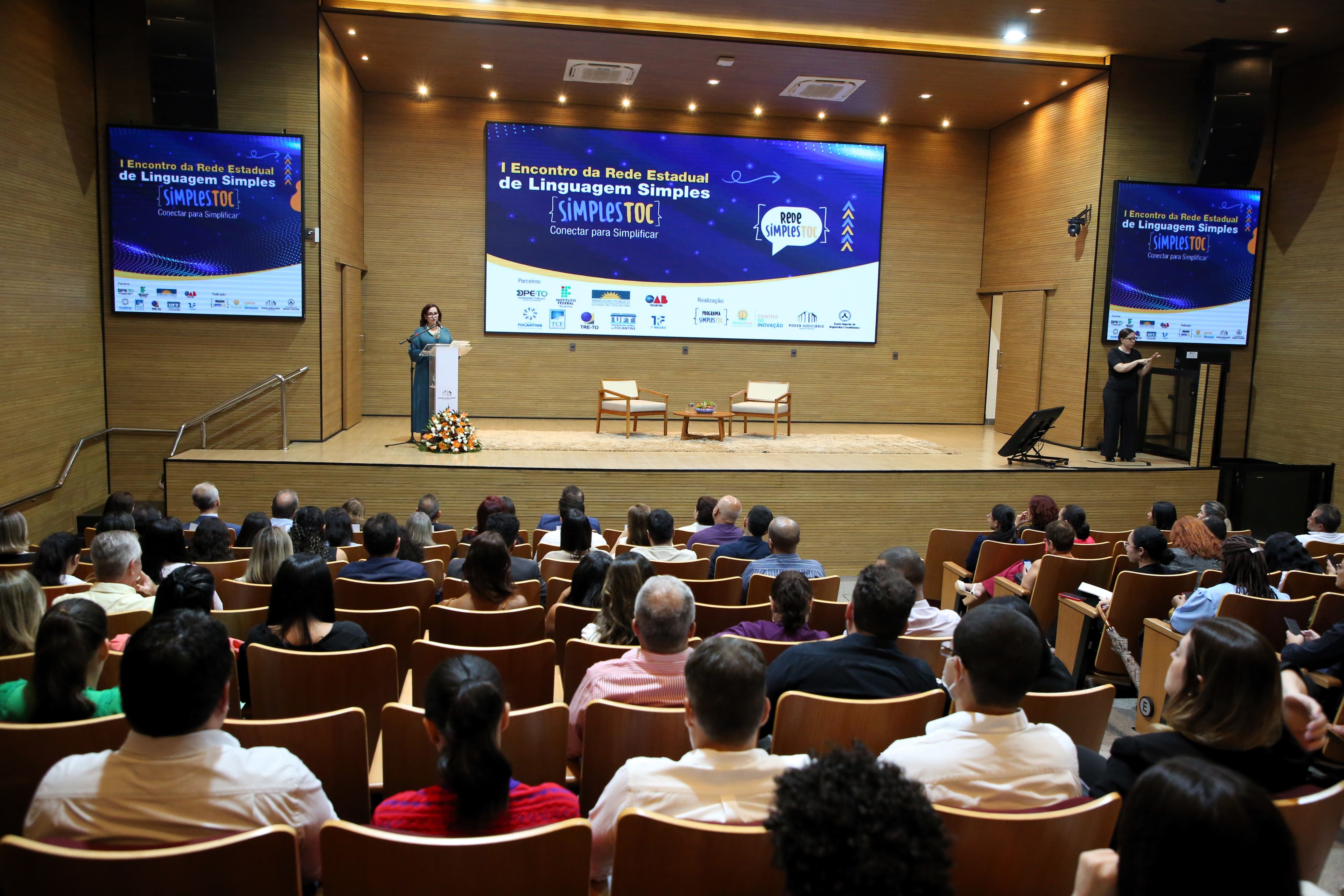 Fotografia colorida que mostra a presidente do TJTO, desa. Etelvina Maria, falando num púlpito observada pela plateia no 1º Encontro do SimplesToc
