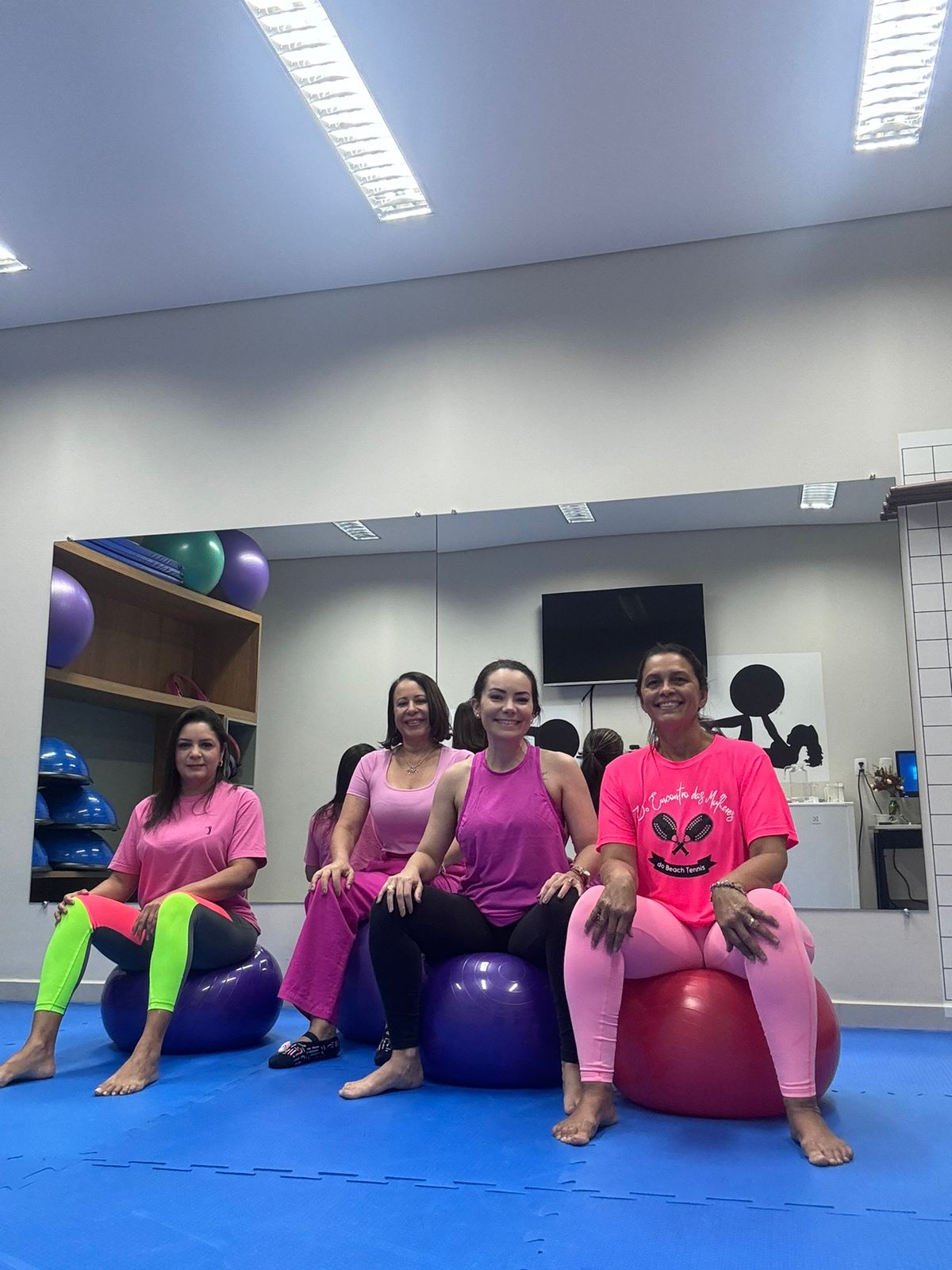 Homens e mulheres sentados em bolas e num tatame descansam depois do mat pilates