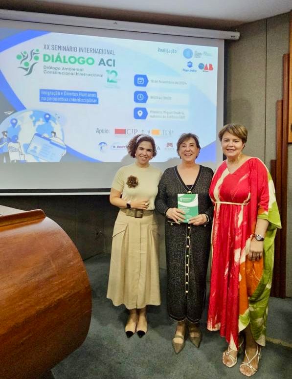 desembargadora Angela Haonat ao sentro, de roupa preta e segurando um livro e as outras duas mulheres ao seu lado, em pé. Roberta à esquerda, de roupa bege e a outra à direita, de roupa vermelha