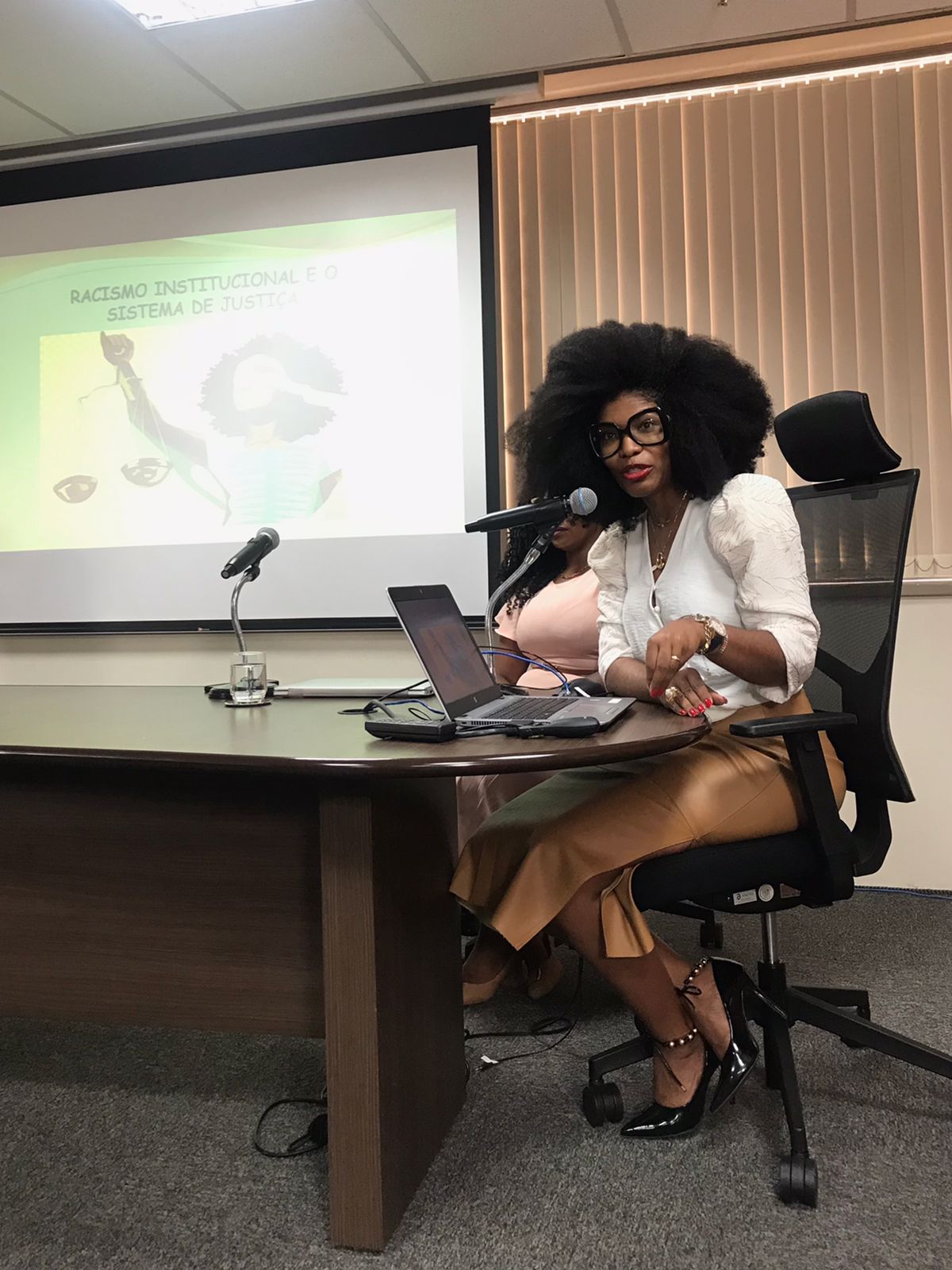 Fotografia colorida de uma mulher negra falando em uma palestra