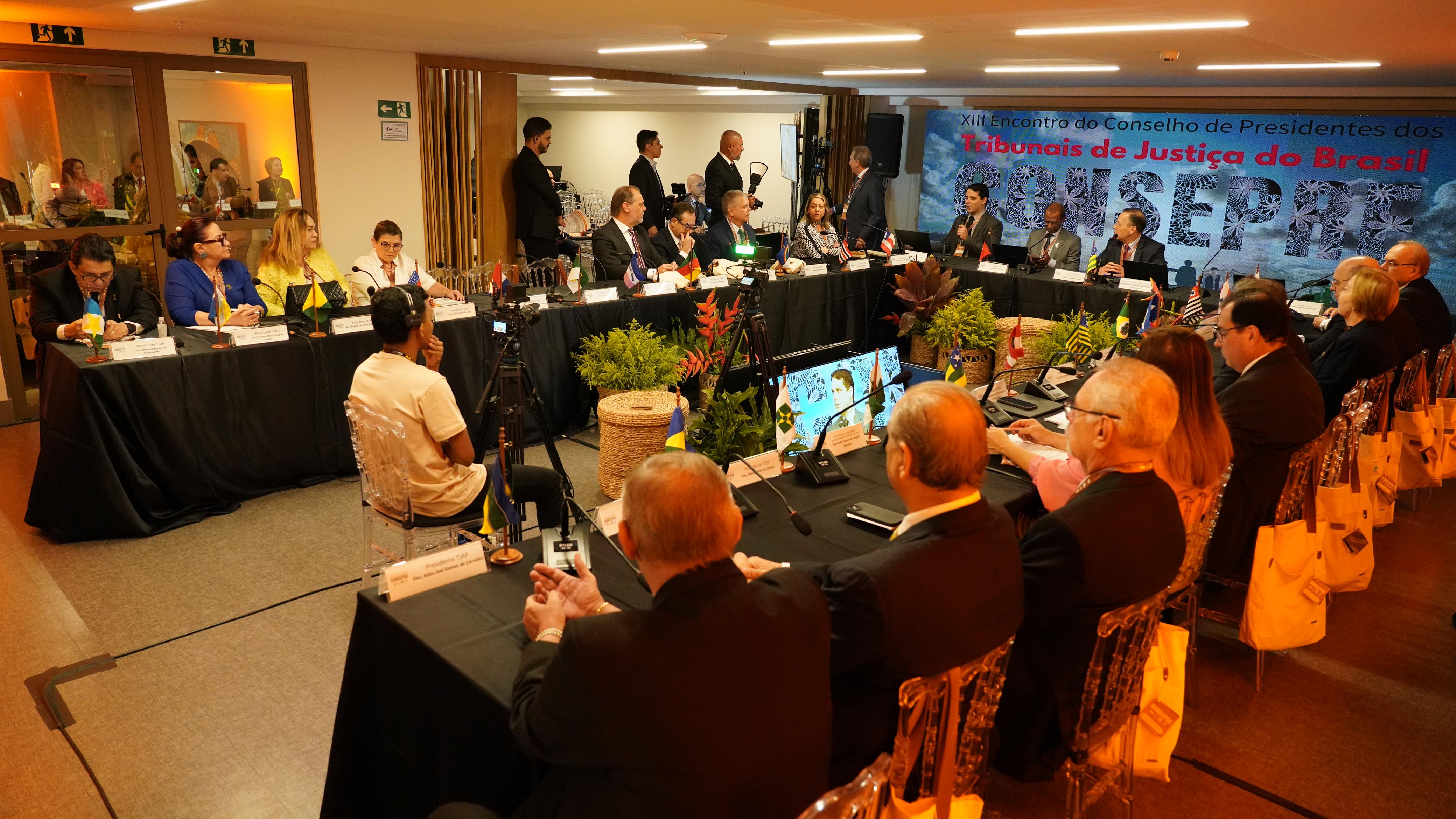 Imagem aberta do salão onde está ocorrendo o evento, com as mesas em formato em U onde estão sentados os presidentes de Tribunais de Justiça do Brasil