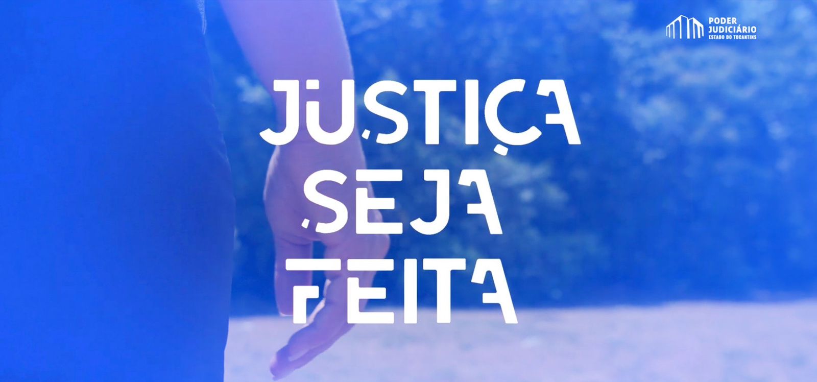 Imagem colorida que mostra uma mão de uma mulher que está de costas, a imagem mostras uma mão e à frente um mato. No card tem a letra Justiça seja feita