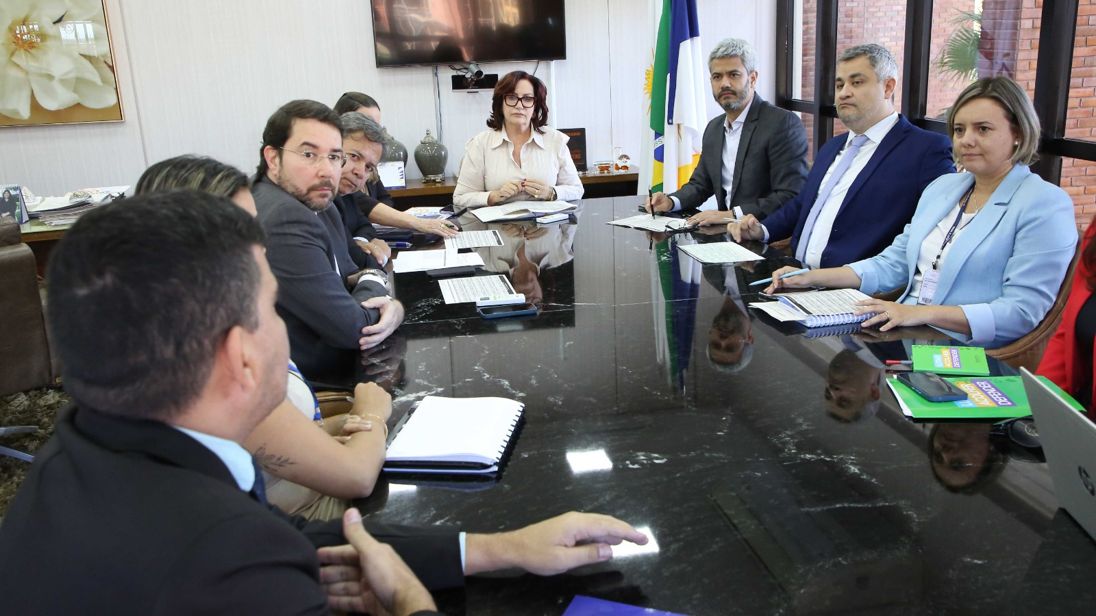 Presidente do TJTO Etelvina Sampaio, corregedora Maysa Vendramini, juízes, procuradores, defensores e servidores do sistema de justiça reunidos em torno da mesa na sala da Presidência do TJTO