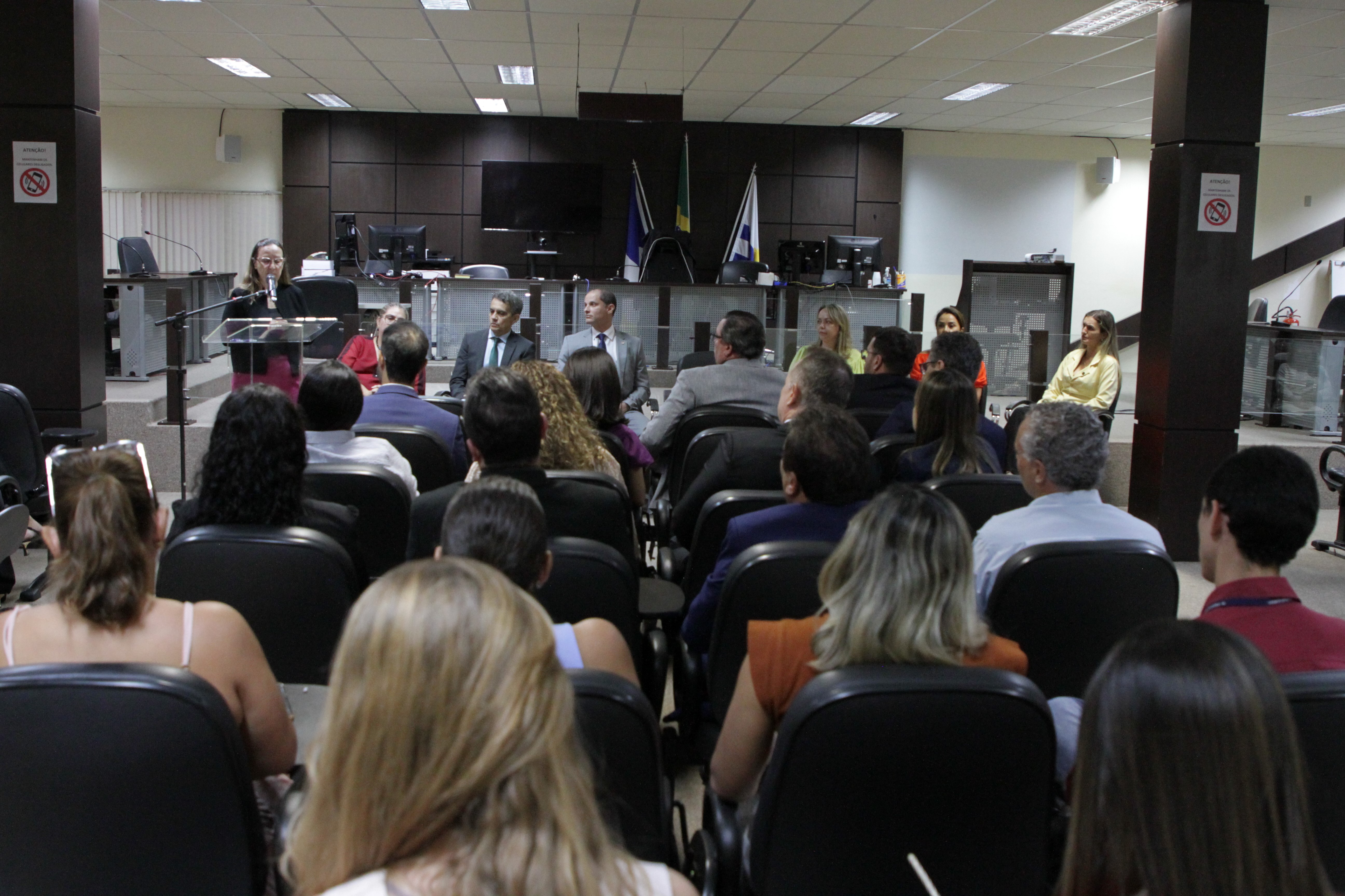 Pessoas sentadas em fileiras de cadeiras voltadas para frente e atentos ouvindo o discurso da corregedora-geral da Justiça do Tocantins.