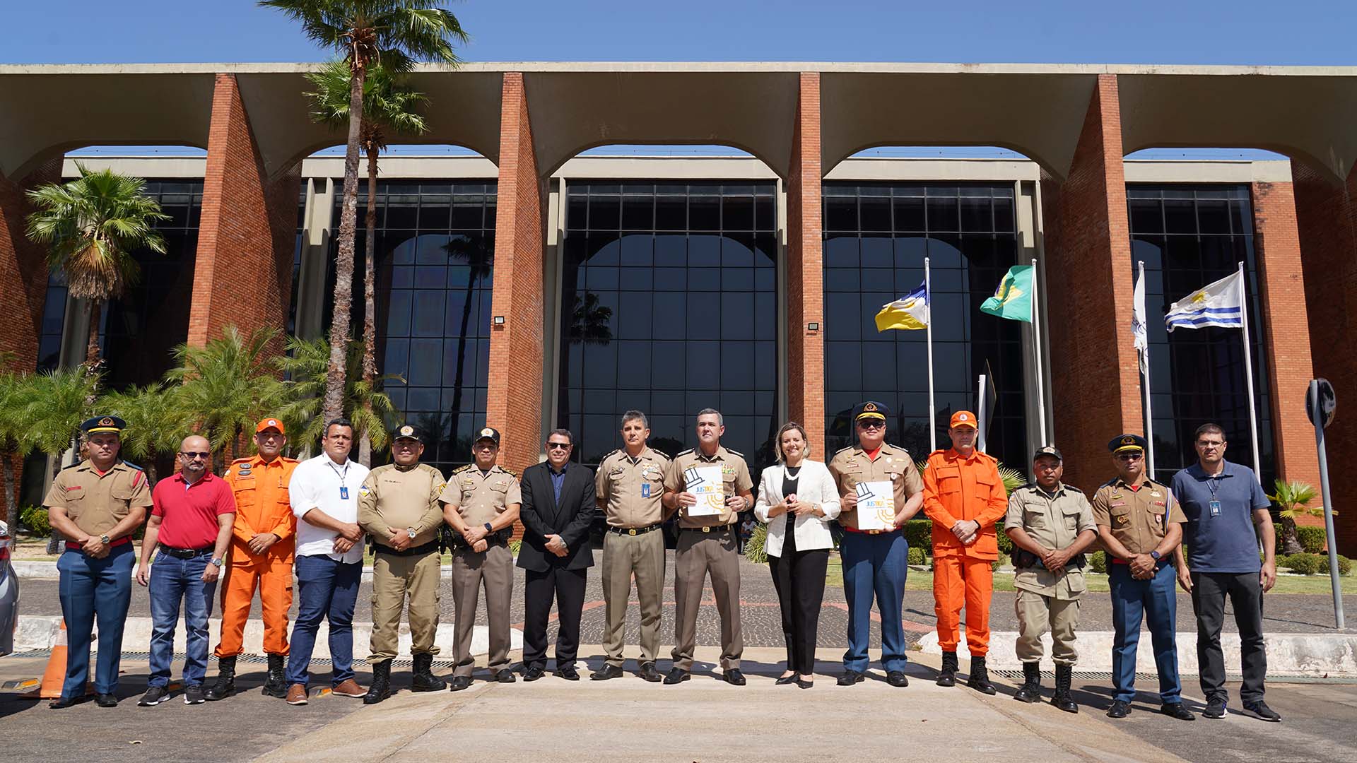 Mulher branca, de blazer branco e calça preta, posa em pé ao lado de homens em frente ao prédio do Tribunal de Justiça do Tocantins