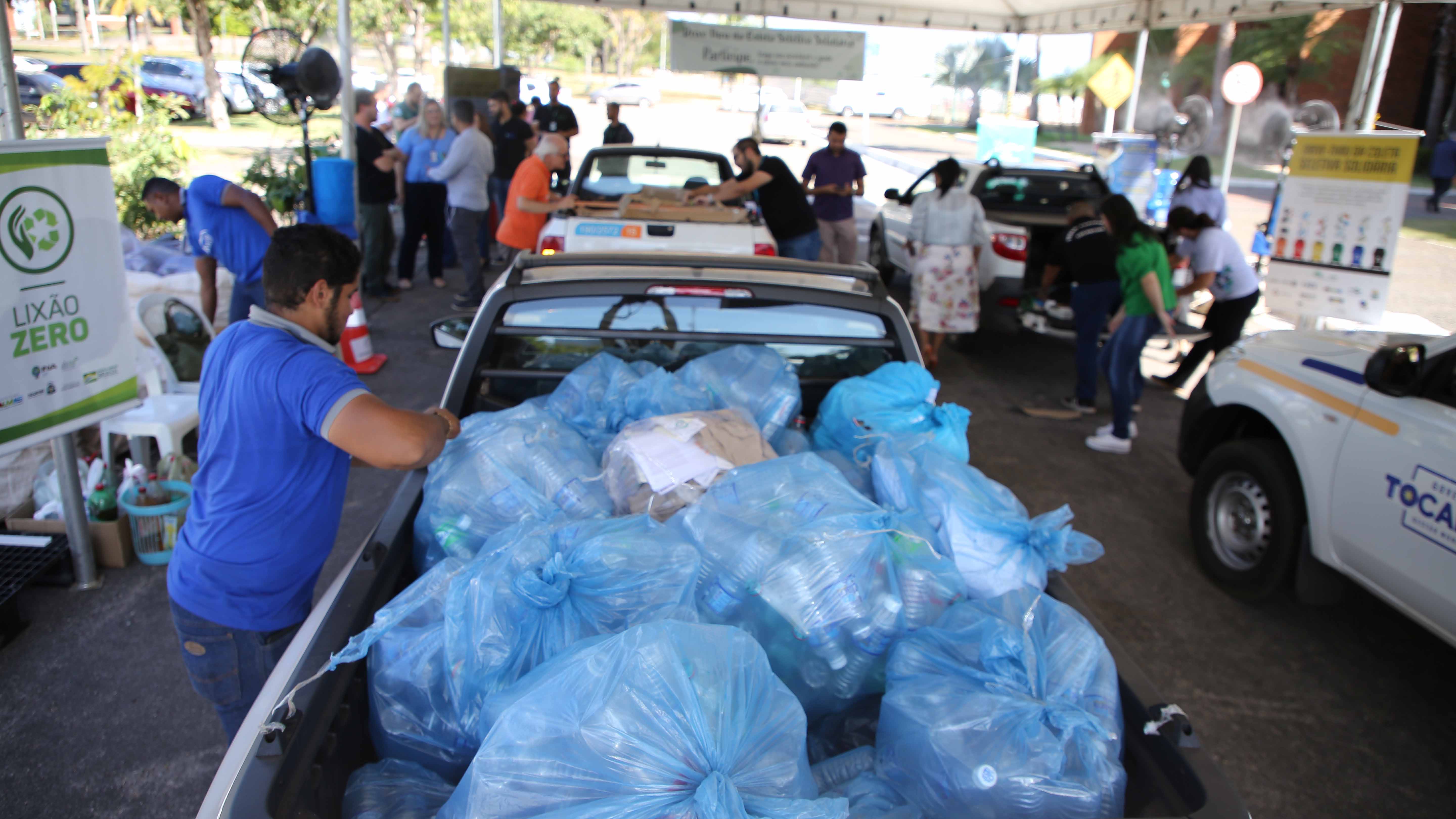 Imagem do Drive-Thru de Coleta Seletiva Solidária do ano passado, com servidores e população participam com doação de resíduos na carroceria de carros, estacionados na porta do TJTO 