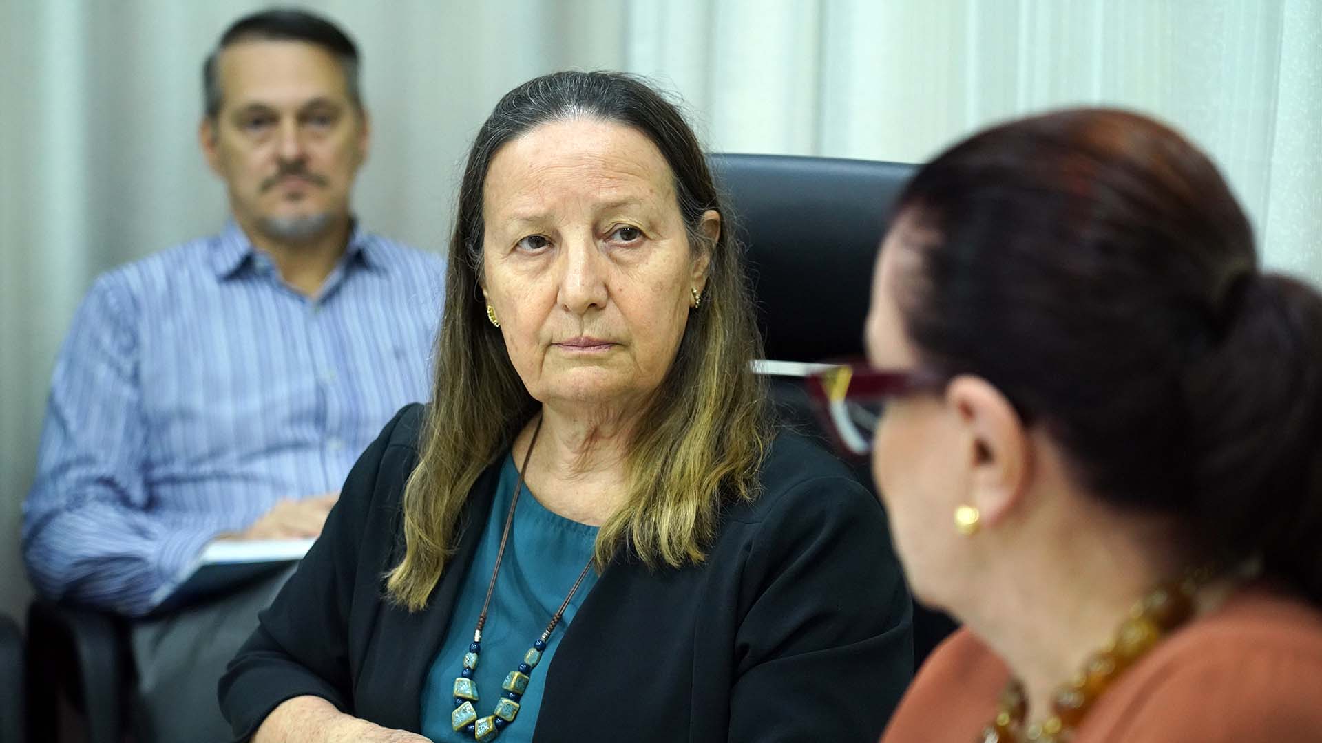 Desembardagora Maysa, de blusa azul e blazer preto, olhando para a desembargadora Etelvina, que aparece ao seu lado direito e usa roupa marrom.