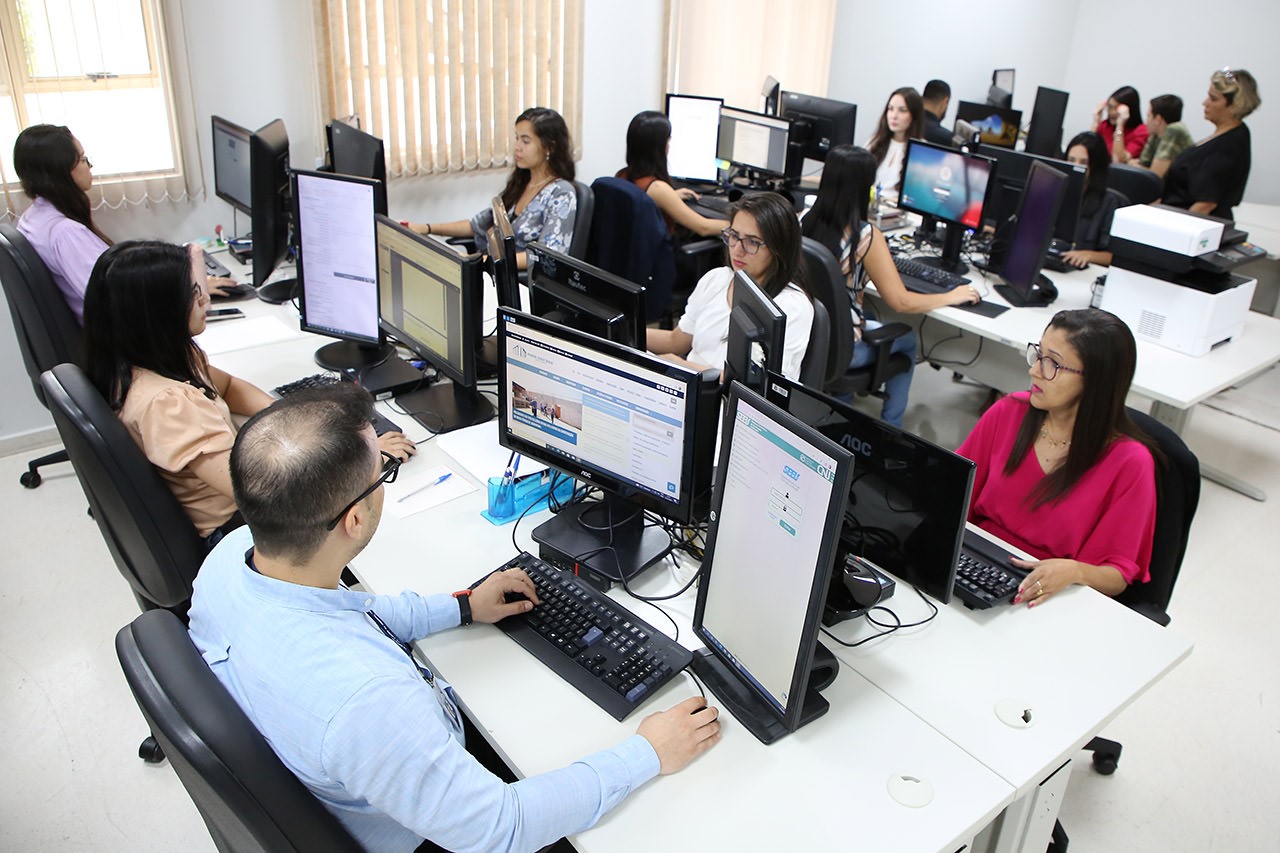 Vários servidores, em uma sala, trabalhando em computadores