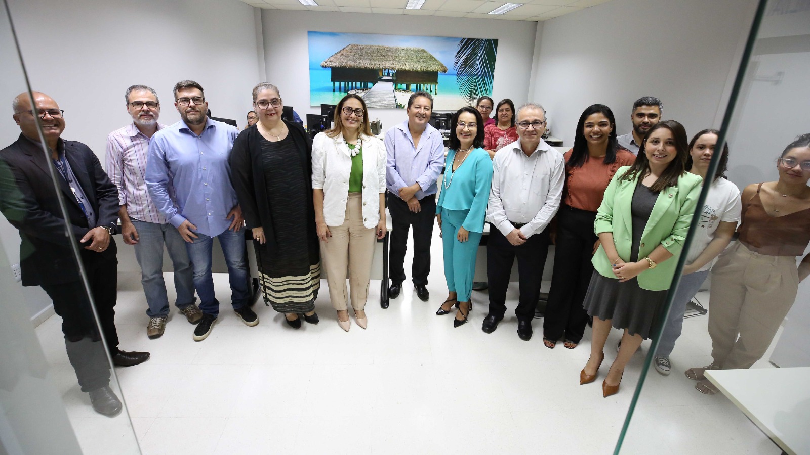 Três pessoas em pé, de frente, sendo magistrados e servidores, na sala da CPE Central 