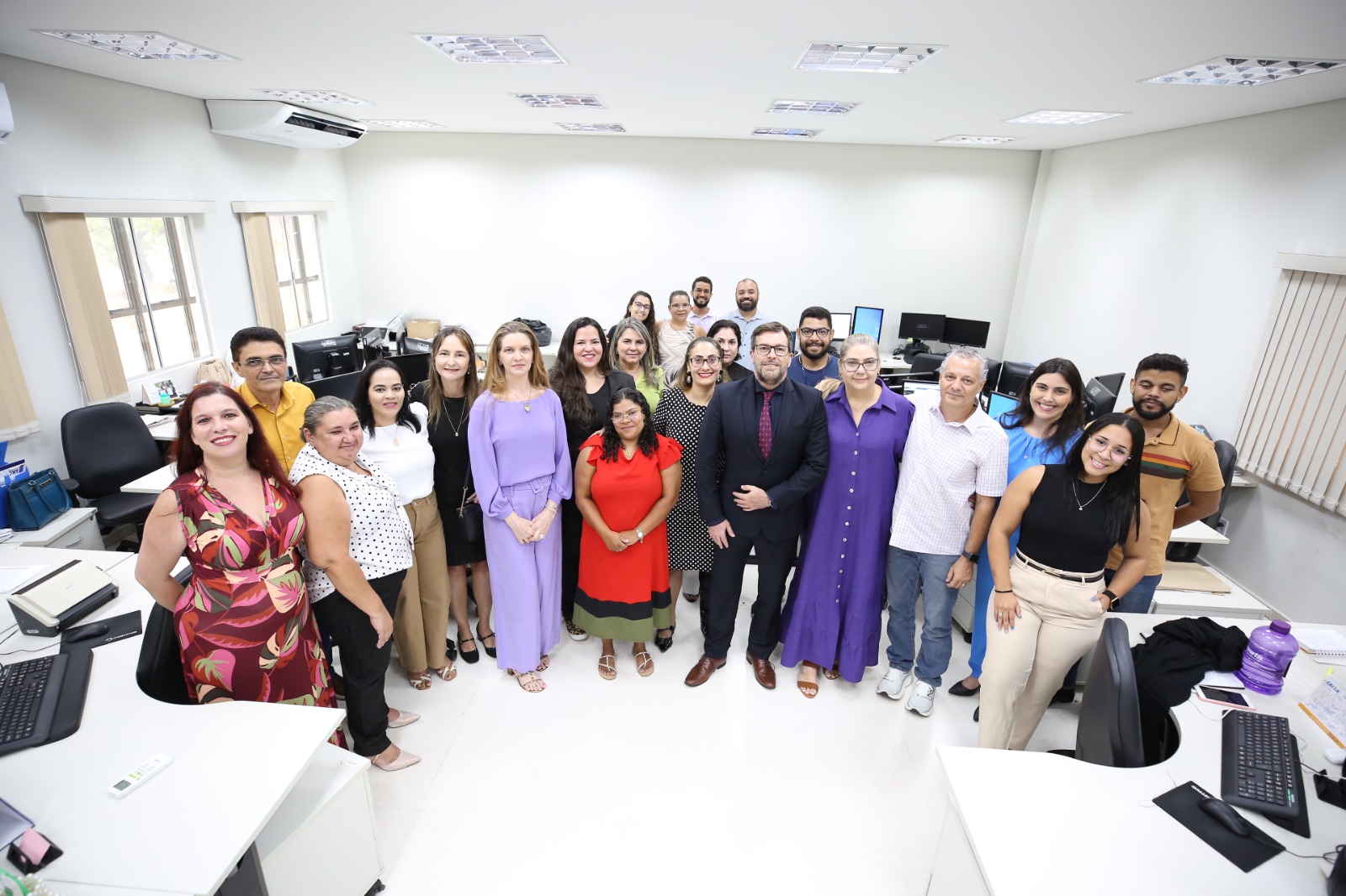 Juízes e servidores dos Juizados Especiais de Palmas em pé, de frente, posando para foto, numa sala de trabalho do Fórum de Palmas