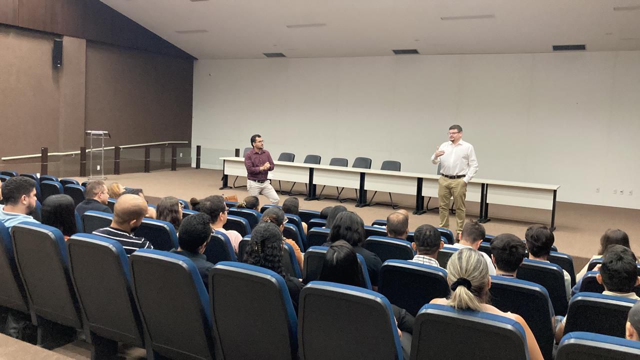 Dois integrantes da equipe do NAPsi reunidos com servidores da Comarca de Araguaína em um auditório; os servidores aparecem de costas olhando para os dois integrantes, que estão de frente, falando aos servidores 