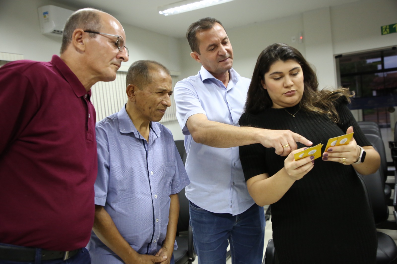 Quatro serviores, sendo três homens e uma mulher, com cartas na mão, jogando o Jogo Simplifique