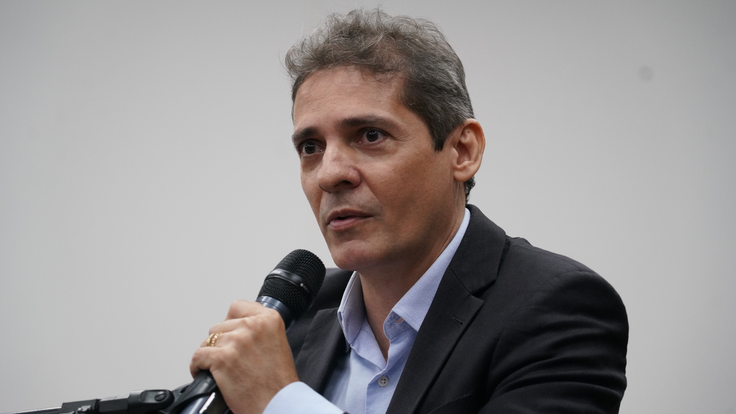 Juiz Herisberto, homem branco, de cabelos grisalhos; ele fala ao microfone e usa blazer escuro e camisa azul-claro