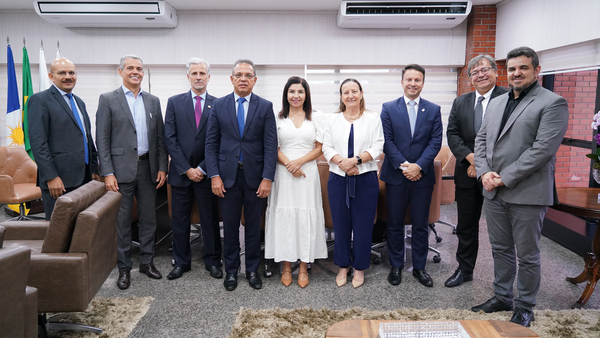 Foto aberta com nove pessoas em pé, de frente e posando para a foto; ao centro, a presidente do TJTO e a procuradora-geral do Estado; os demais são magistrados, diretores e secretários do Governo do Estado