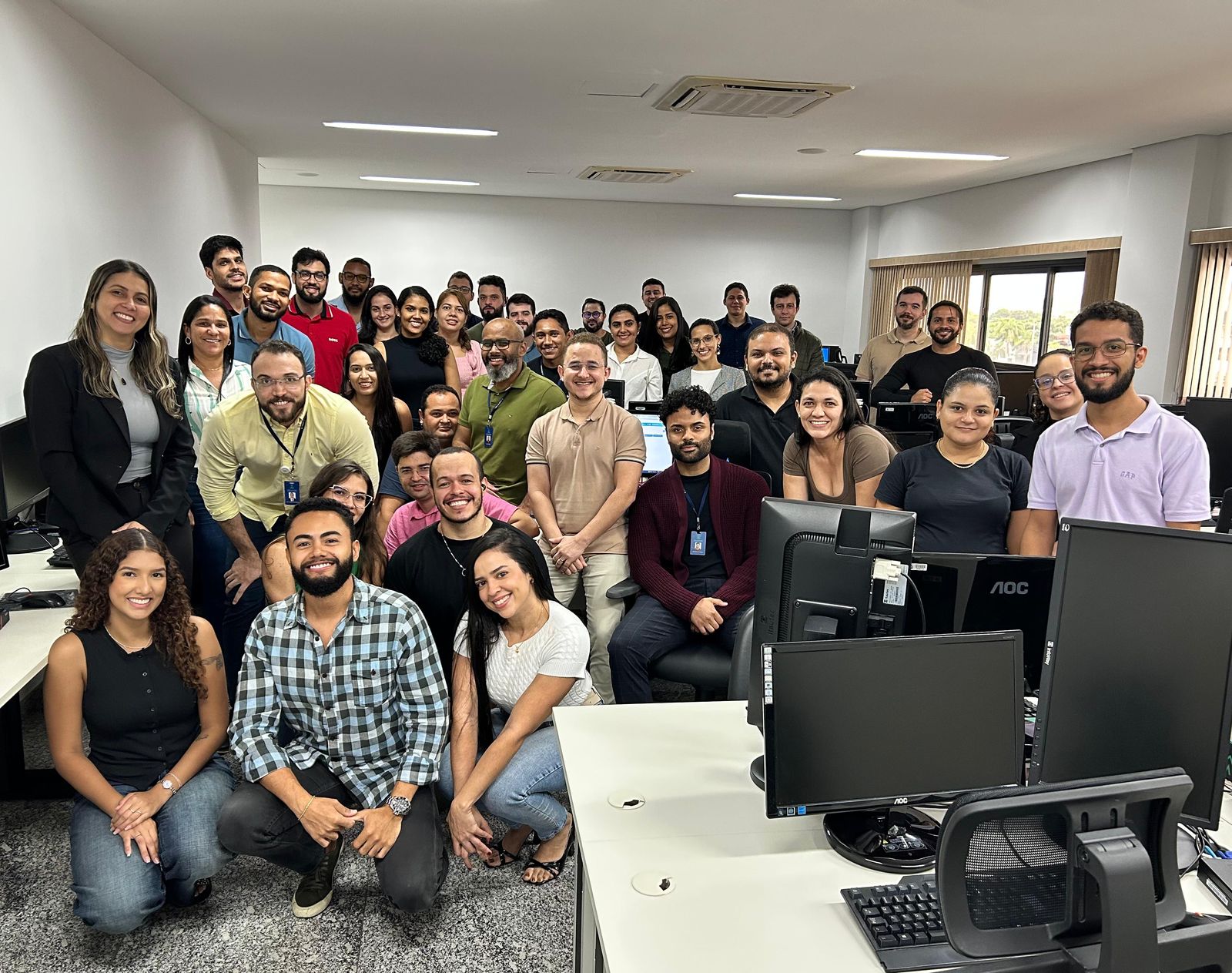 Imagem aberta com vários servidores numa sala posando para a foto, ao lado de mesas e computadores
