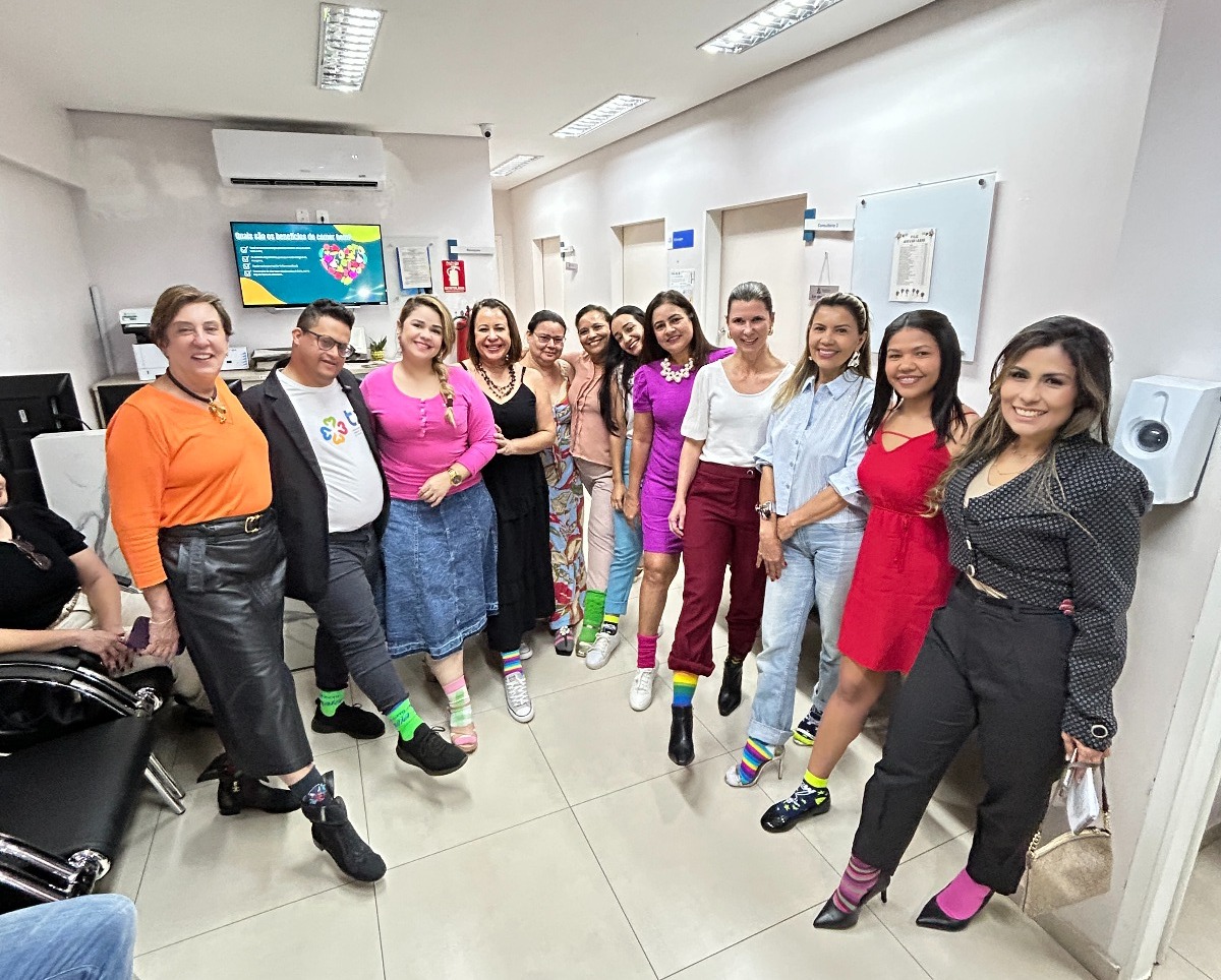 Homens e mulheres em pé mostrando as meias coloridas. Uma campanha alusiva ao Dia Mundial da Síndrome de Down