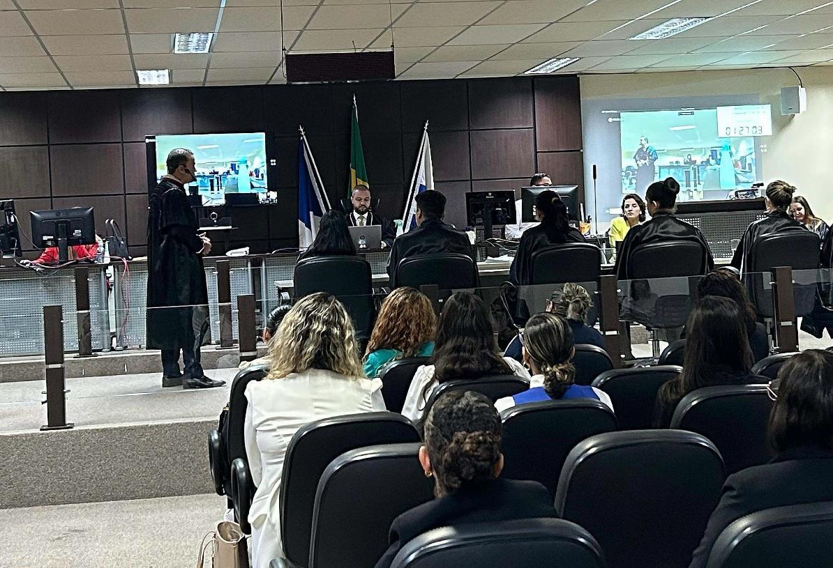 Imagem de um tribunal, com pessoas em trajes formais, reunidas em uma sala de audiências.