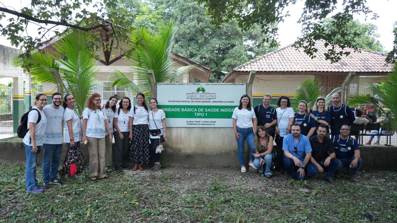 Imagem mostra um grupo de vários profissionais de saúde voluntários em frente a um centro de saúde indígena.