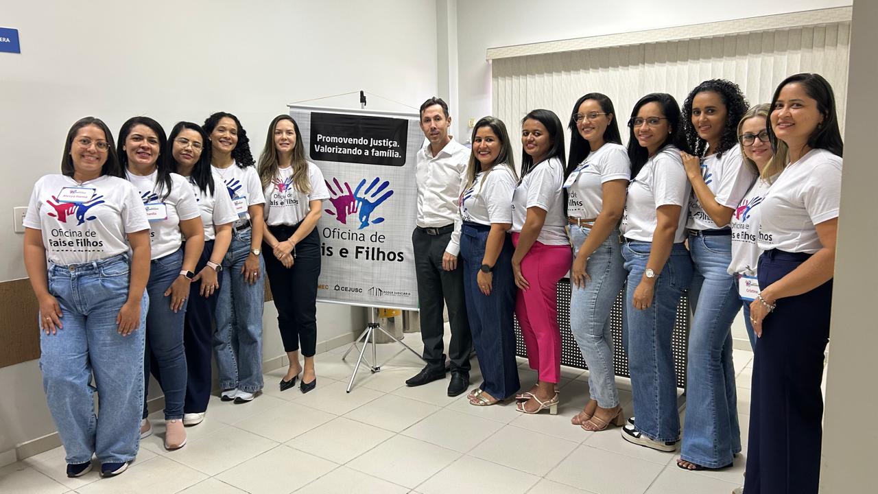 Juiz Fabiano com a equipe que trabalhou na oficina em Araguaçu. Na foto, 12 pessoas, sendo o juíz e 11 mulheres vestidas com camiseta branca com a logo e nome: Oficina de Pais e Filhos; ao centro um banner btanco da  oficina