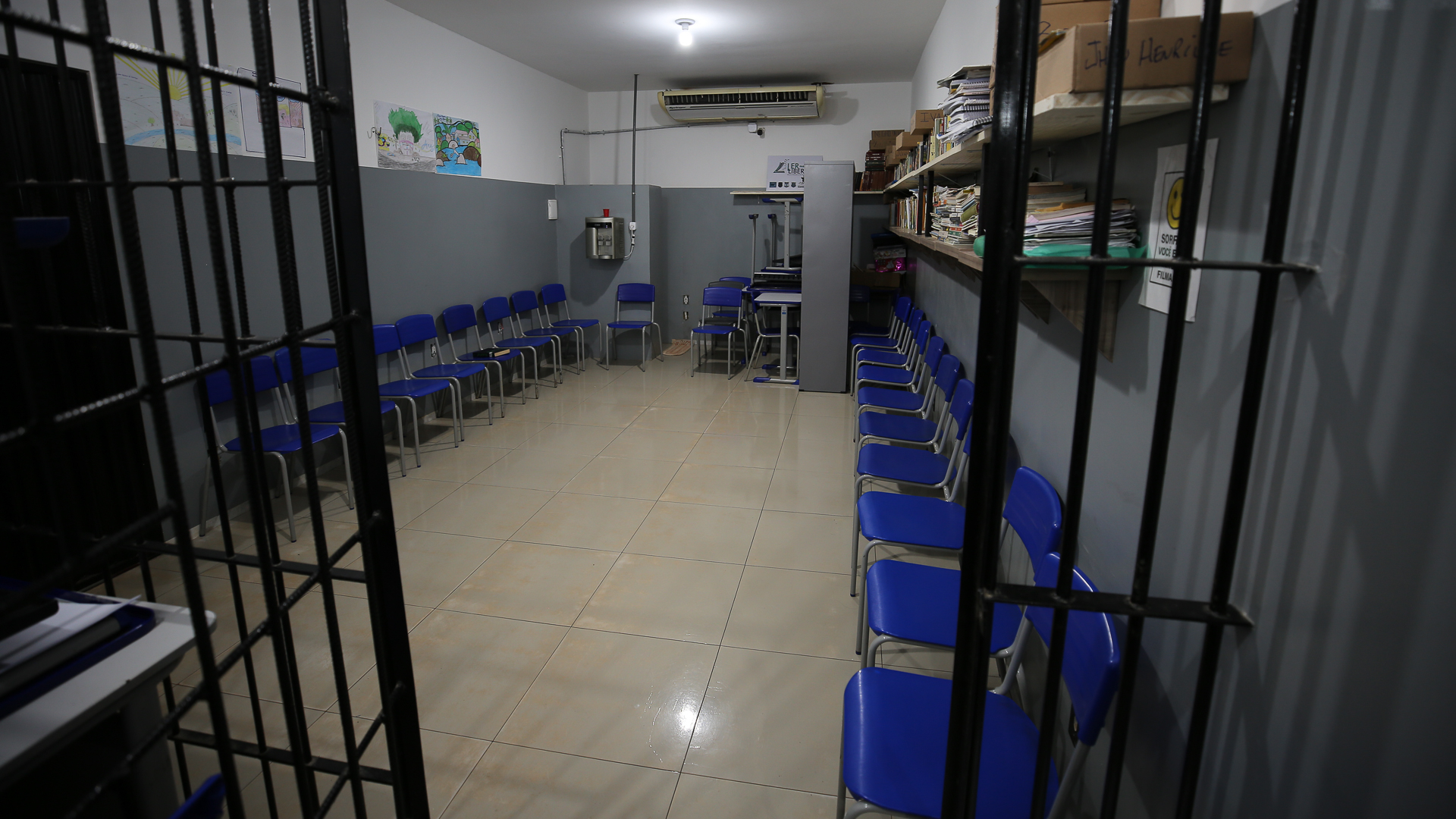 A imagem apresenta uma montagem com o antes e o depois da reforma de uma cela na unidade penal de Tocantinópolis. Detentos aparecem de costas, com as mãos sobre a cabeça. No lado esquerdo, é possível ver a cela em condições precárias, com paredes danificadas e baldes espalhados pelo chão. No lado direito, a cela reformada exibe paredes pintadas, ambiente limpo e a instalação de um beliche.