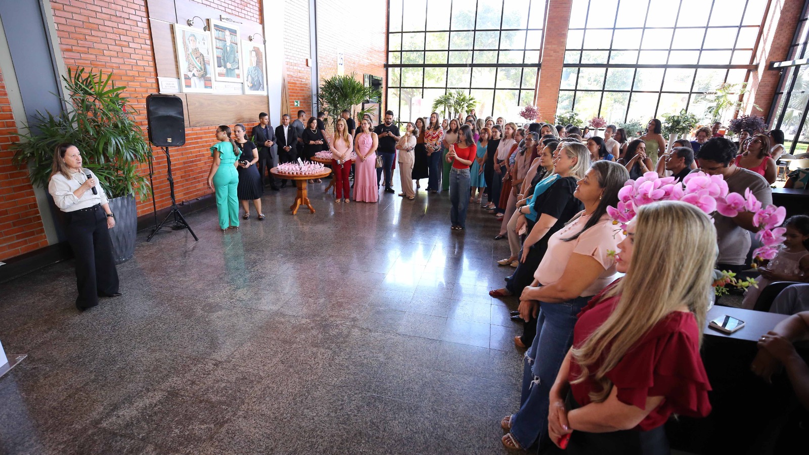 Foto mostra a desembargadora Maysa de frente, falando ao microfone para um grande número de mulheres reunidas durante o evento.