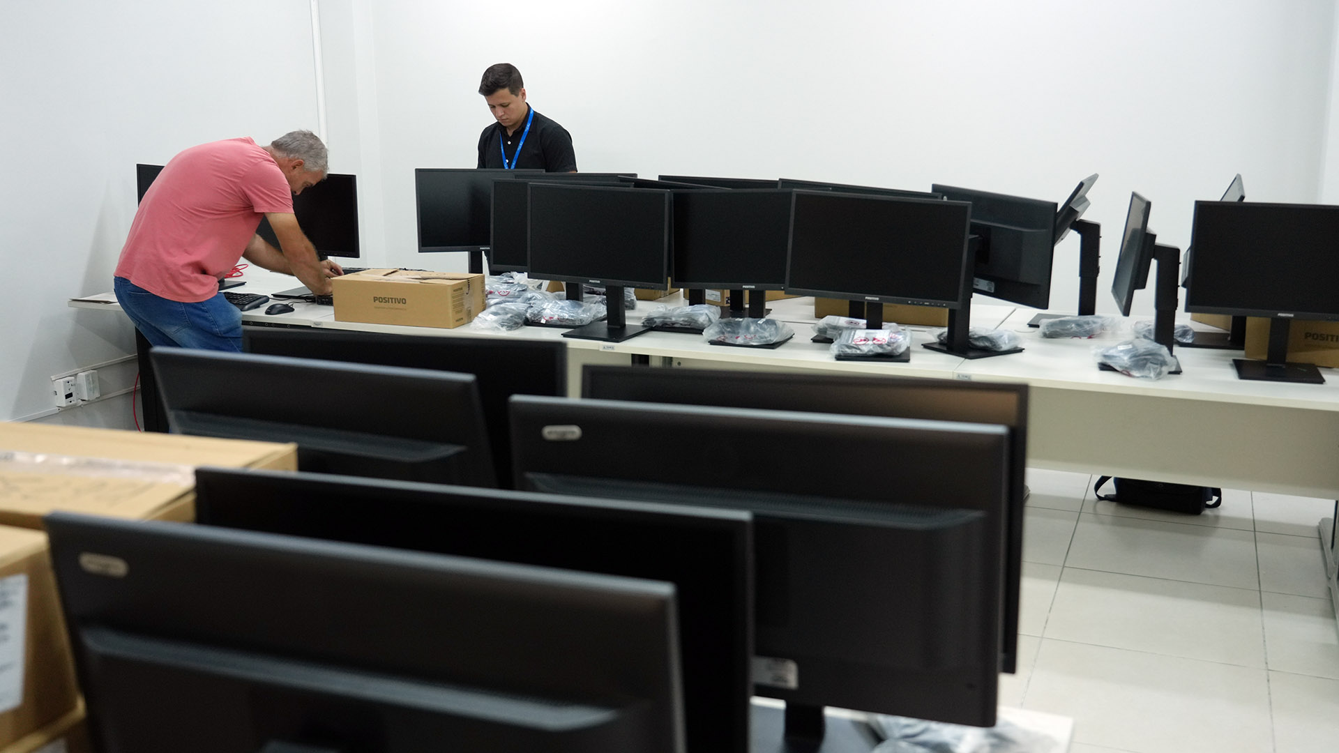 A imagem mostra dois servidores durante a instalação de dezenas de computadores no Núcleo de Apoio às Comarcas, em substituição aos equipamentos antigos.