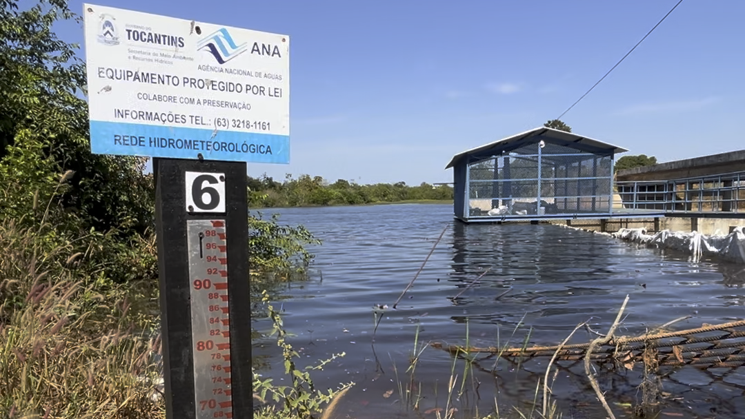 Placa com uma régua em primeiro plano e ao fundo um reservatório 