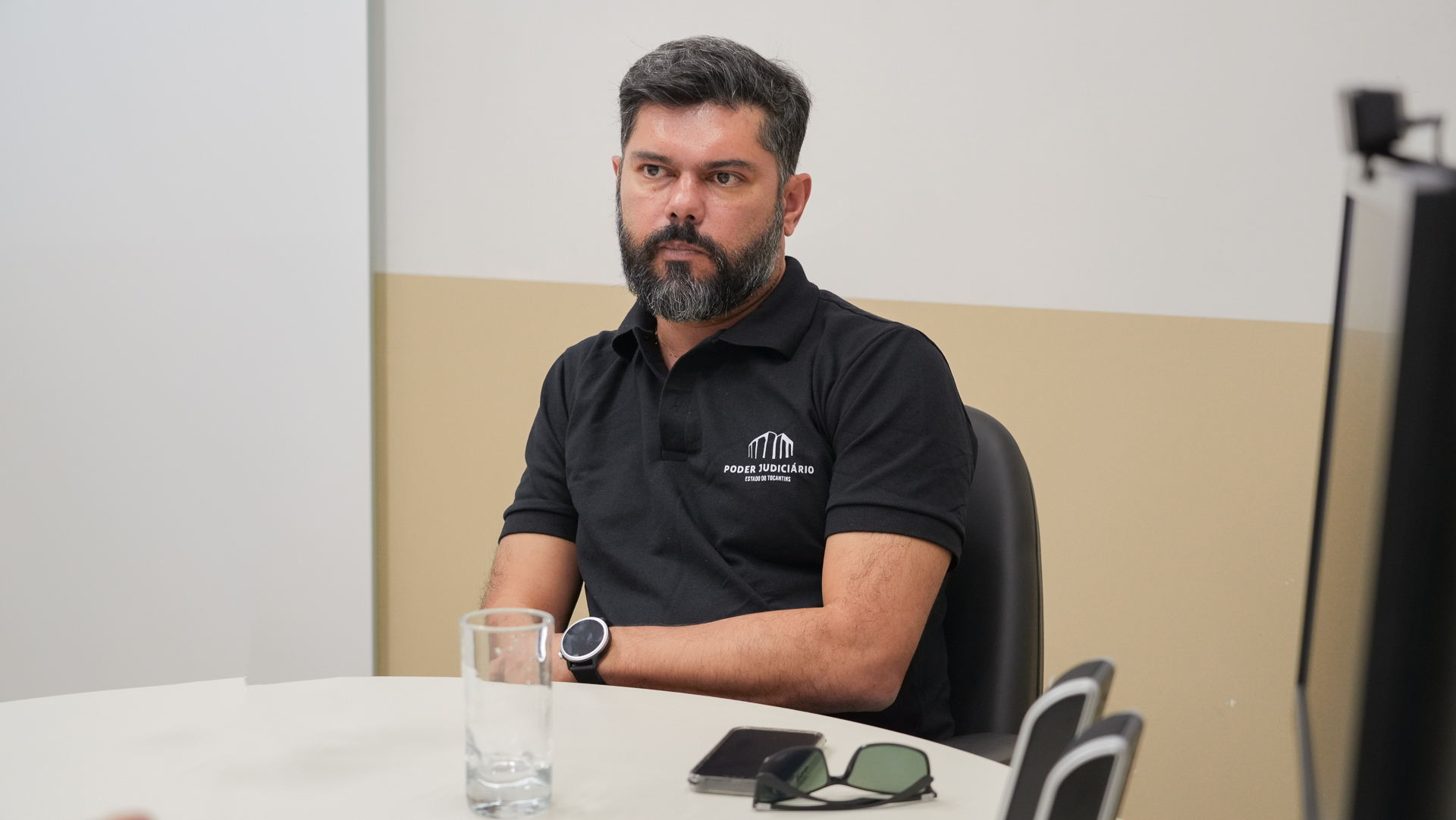 Juiz Wellington, homem moreno claro, cabelos e barba grisalhos; ele está sentado e usa camiseta preta com o nome: Poder Judiciário do Tocantins