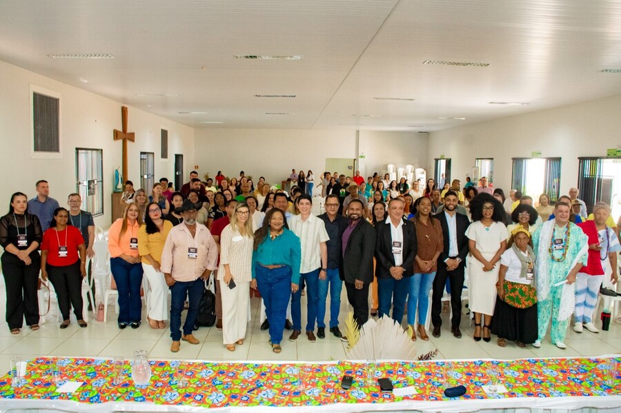 Imagem aberta com a juíza e demais participantes da conferência em pé, posando para a foto