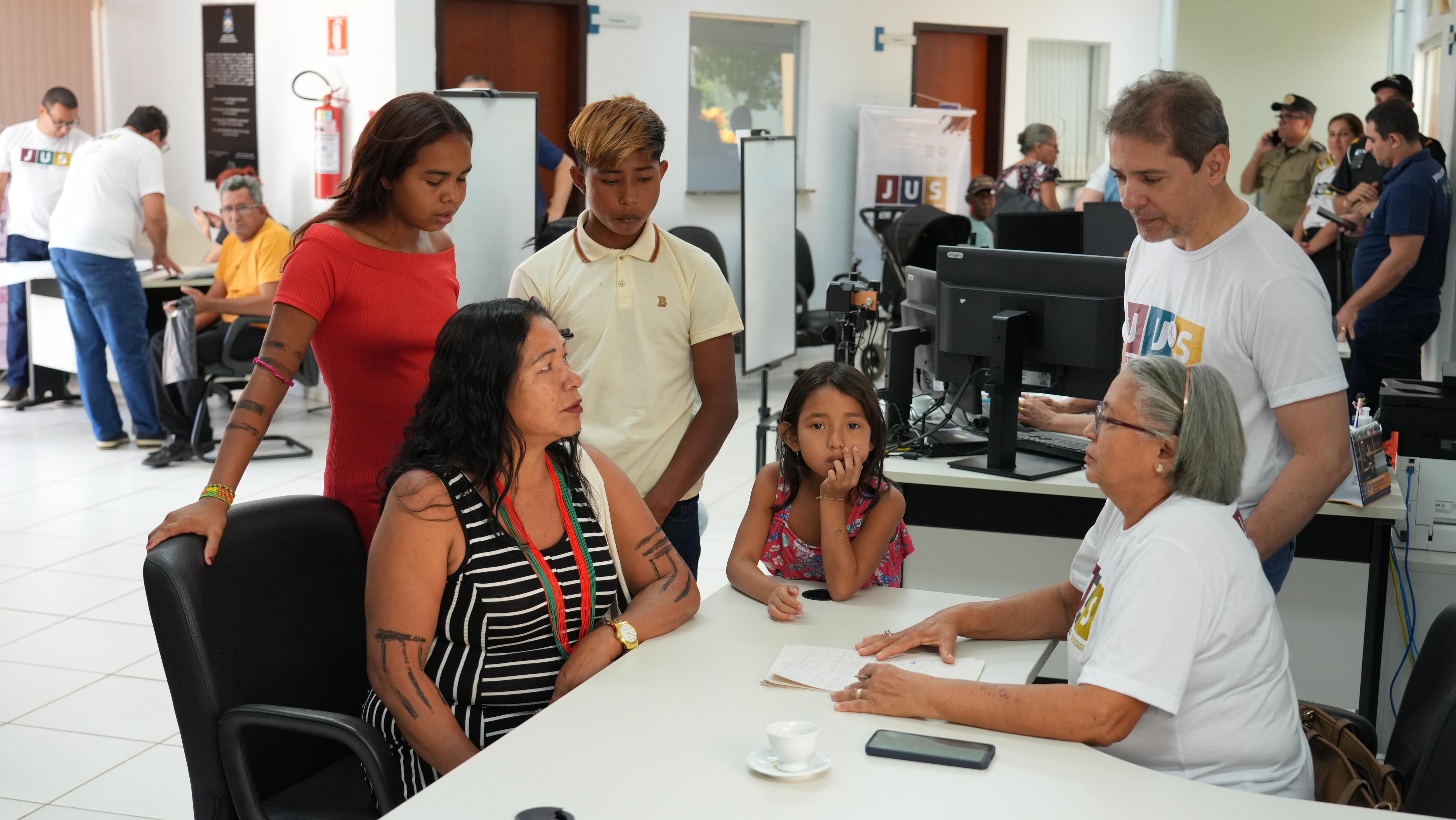 Família indígena recebendo atendimento em ação de cidadania do Poder Judiciário 
