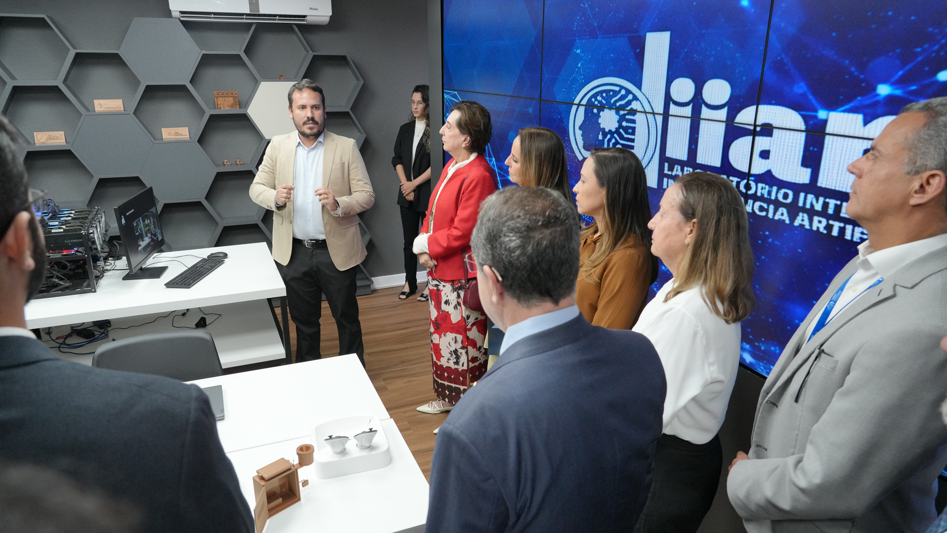 Foto aberta de desembargadores e diretores ouvindo explicações do professor coordenador científico do laboratório