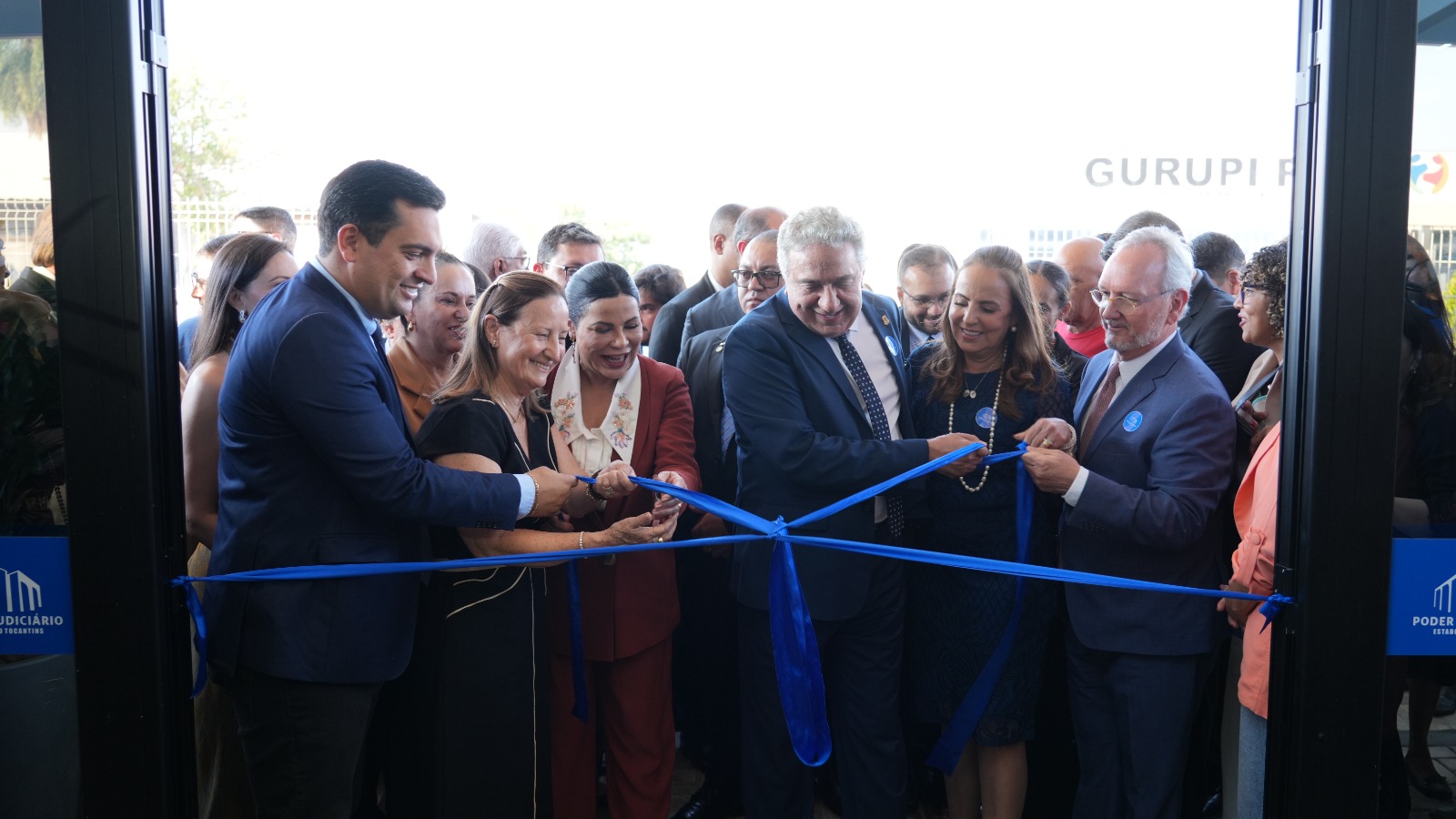 Imagem do desenlace da fita inaugural na porta de entrada do Fórum de Gurupi; ao fundo as autoridades e convidados 