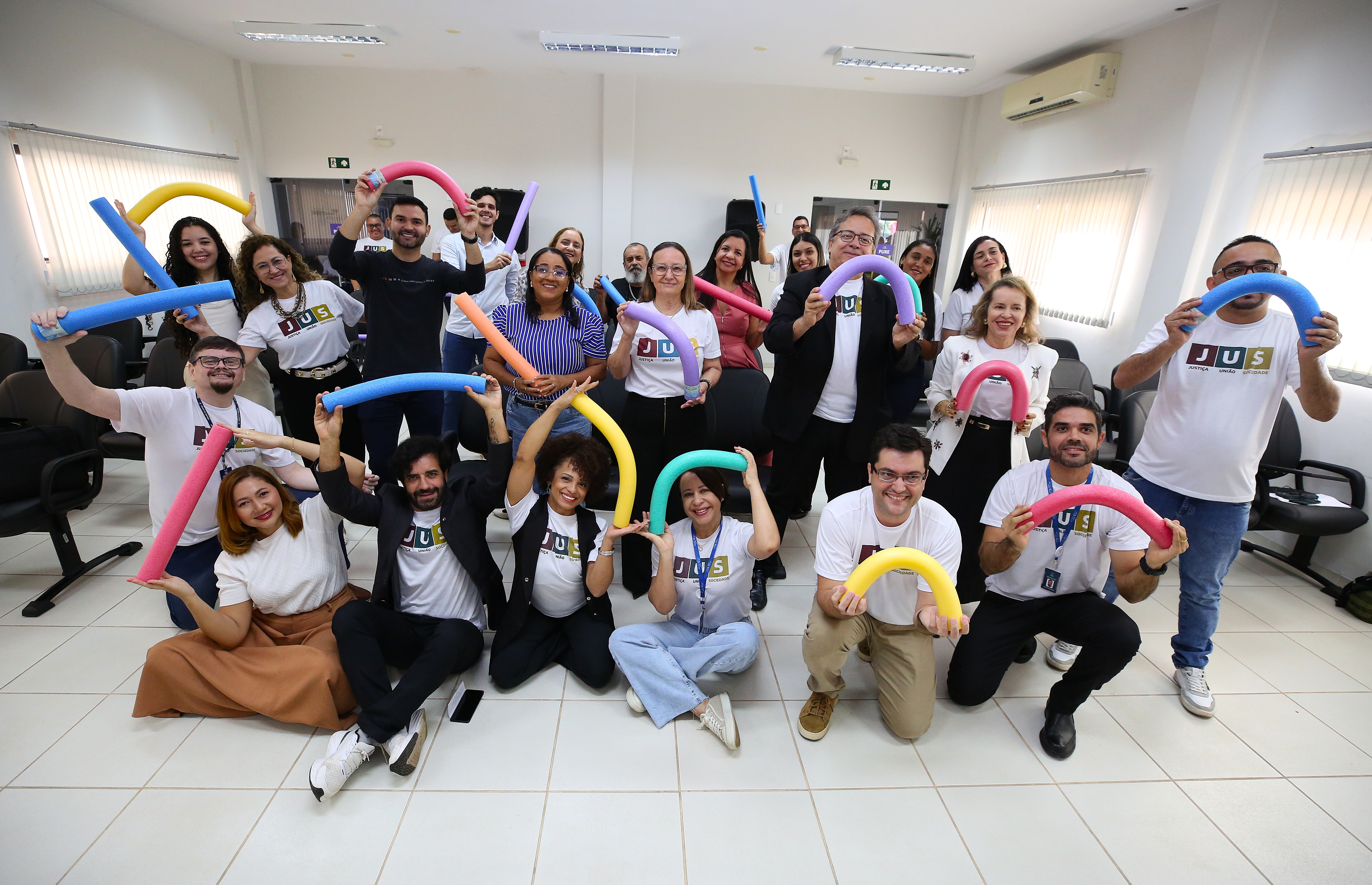 Homens e mulheres posando para foto segurando aparato de fisioterapia "macarrão" 