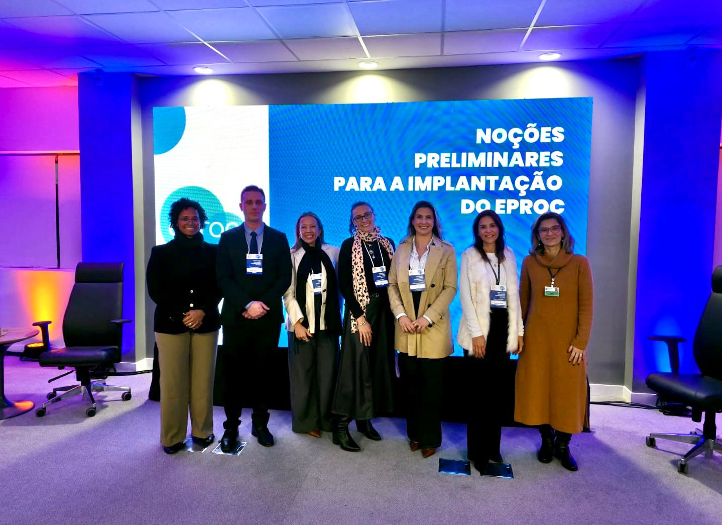 Foto posada com sete pessoas em pé, de frente, sendo seis mulheres e um homem, durante capacitação em Porto Alegre. Ao fundo um painel com o nome da capaciatação: Noções Preliminares para a Implantação do eproc