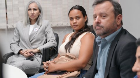 Daniele participa de audiência ao lado de representantes do sistema de Justiça, com expressão atenta durante o atendimento.
