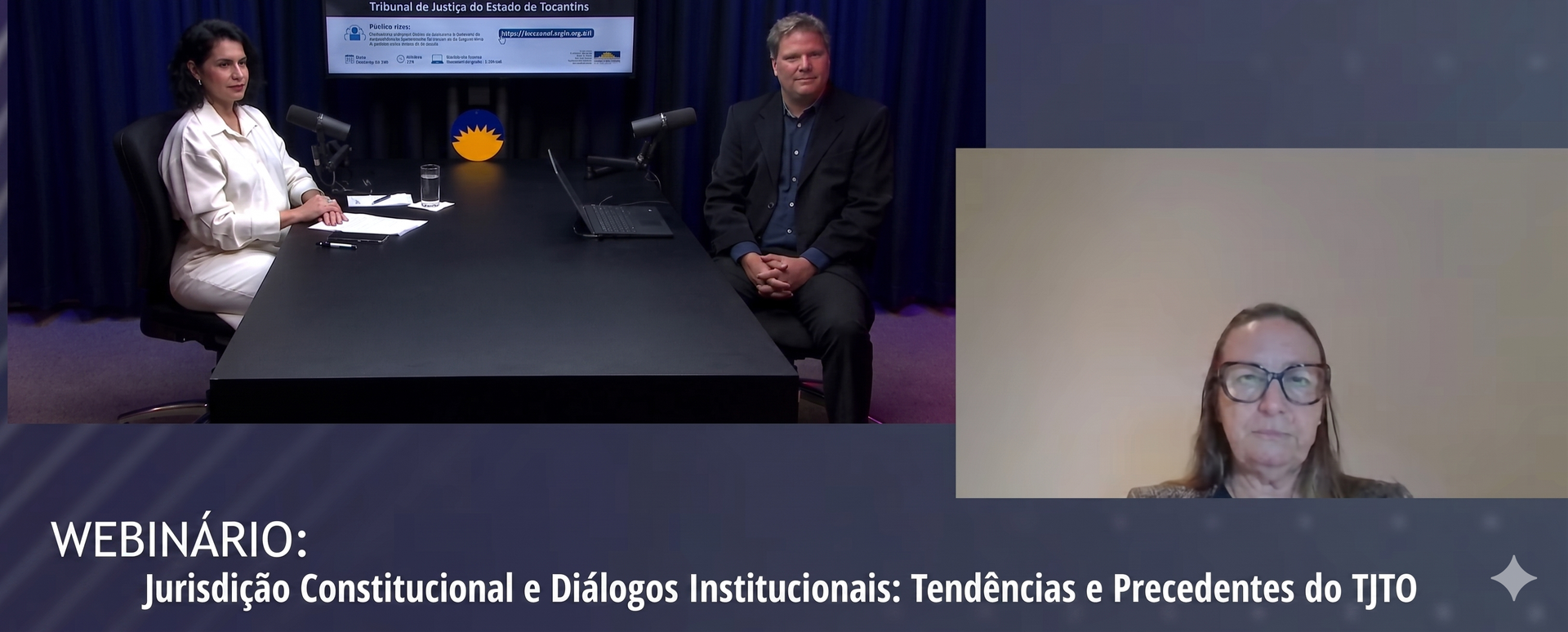 Imagem de um webinário do Tribunal de Justiça do Tocantins, com dois participantes em estúdio, sentados à mesa com microfones e notebook, e uma participante remota em tela ao lado. Ao fundo, aparece a identidade visual do evento. Na parte inferior, o título: “Webinário: Jurisdição Constitucional e Diálogos Institucionais: Tendências e Precedentes do TJTO”.