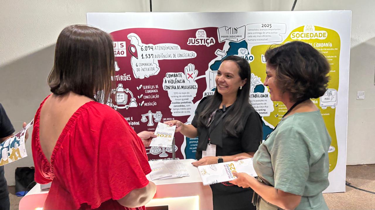 A imagem mostra três mulheres em um ambiente interno, possivelmente institucional, interagindo em um estande informativo. Uma delas, vestida de preto e usando crachá, sorri enquanto entrega um material impresso para outra mulher, que está de costas e veste uma blusa vermelha. Ao lado, uma terceira mulher, com blusa verde, segura um folheto semelhante e observa a interação.  Ao fundo, há um painel colorido com informações sobre ações do Poder Judiciário, incluindo dados de atendimentos, audiências de conciliação e iniciativas voltadas à cidadania e ao combate à violência contra a mulher. O ambiente sugere uma ação de orientação ou divulgação de serviços à população.
