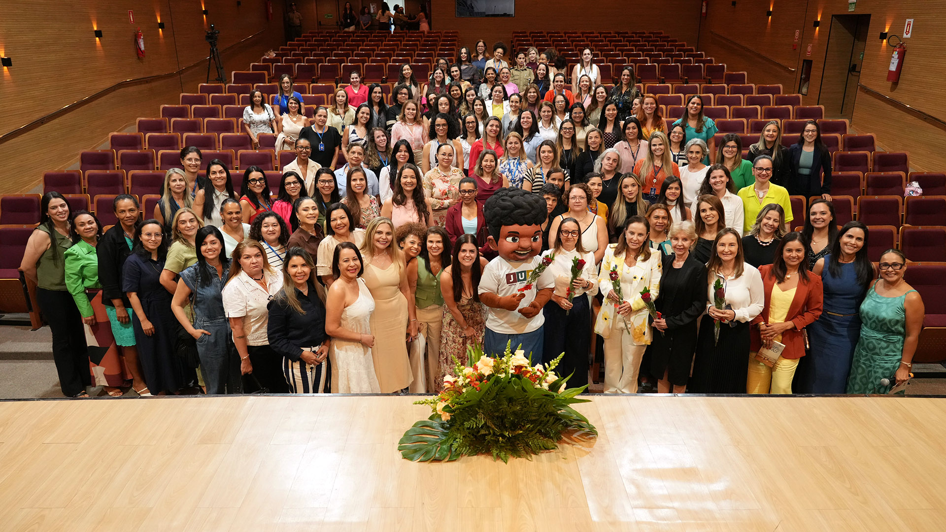 Dezenas de mulheres servidoras, além do mascote do programa JUS, posa para foto no auditório do TJTO após evento do Dia das Mães