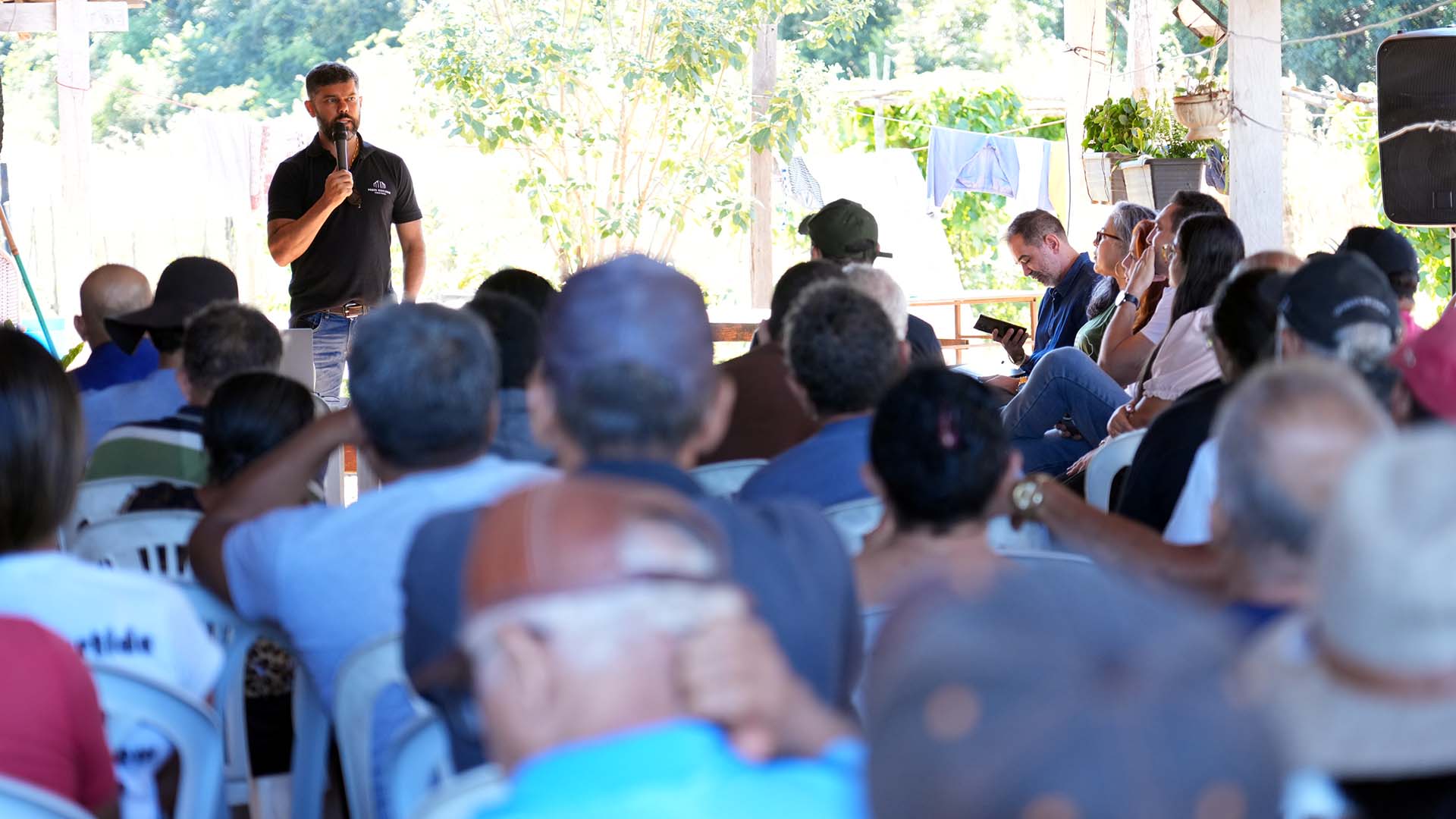 O juiz Wellington Magalhães fala ao público durante reunião realizada na área da Fazenda Serra Dourada, em Palmas. Sentados em cadeiras plásticas, moradores e representantes das instituições acompanham a fala do magistrado.