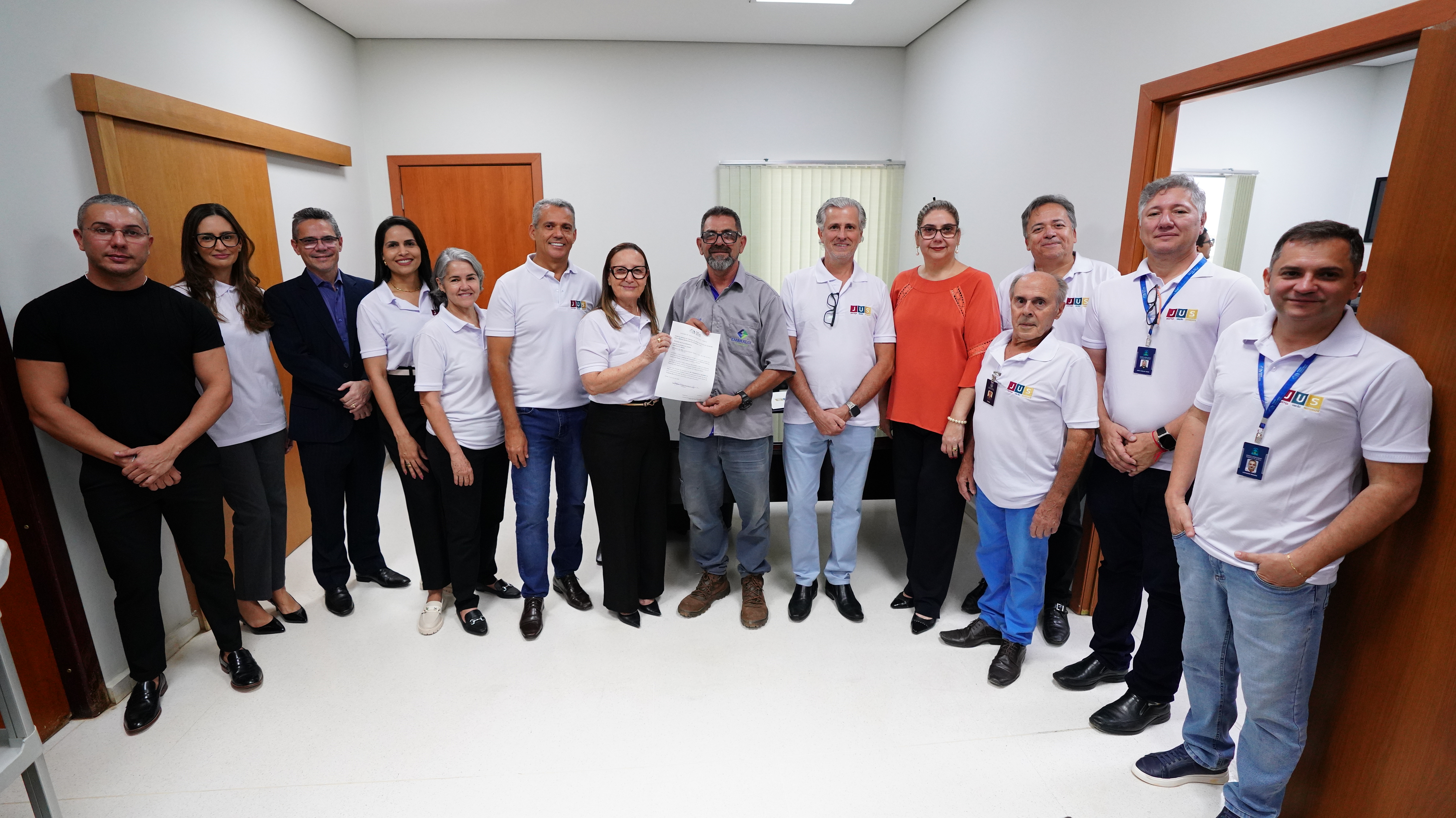 Comitiva de pessoas da Presidência do TJTO perfiladas em uma sala com a exibição da ordem de serviço para troca de elevadores do prédio de Palmas
