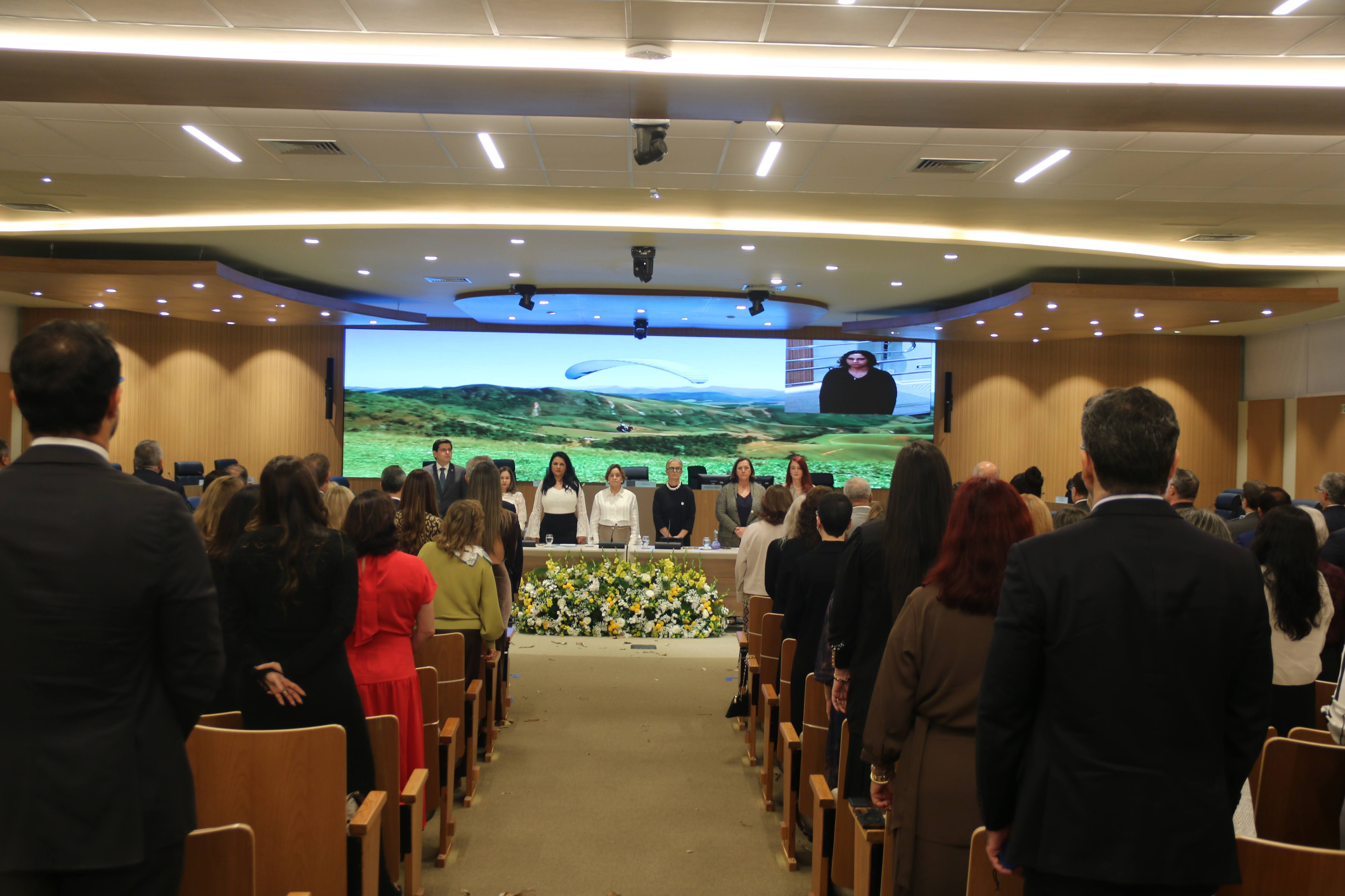 A imagem mostra a solenidade de abertura do VII Encontro do Colégio de Ouvidorias Judiciais das Mulheres (COJUM), realizada em Vitória (ES), com a participação de representantes de tribunais de diversas regiões do país.