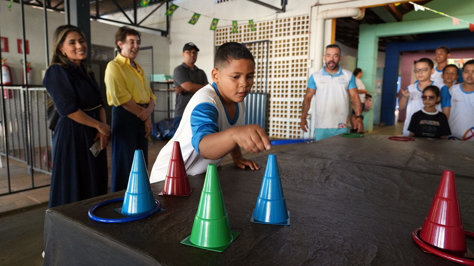 A presidente da Comissão Permanente de Acessibilidade e Inclusão (CPAI) do Tribunal de Justiça do Tocantins, desembargadora Angela Haonat, e a secretária executiva da comissão, Patrícia Idehara, acompanham uma atividade esportiva durante o 1º Festival TEAtivo – Copa do Mundo, na Apae de Palmas. A prova integra as ações do projeto, que utiliza o esporte para estimular a inclusão, a socialização e o desenvolvimento de estudantes com Transtorno do Espectro Autista (TEA).