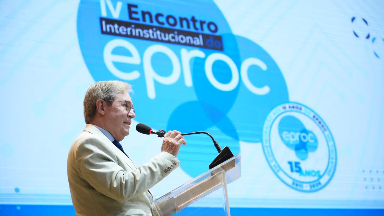 O presidente do Tribunal Regional Federal da 4ª Região (TRF4), desembargador João Batista Pinto Silveira, discursa na abertura do IV Encontro Interinstitucional do eproc, no auditório do Tribunal de Justiça do Tocantins. Ao fundo, o painel do evento exibe a identidade visual do encontro e o selo comemorativo dos 15 anos do eproc no Judiciário tocantinense.