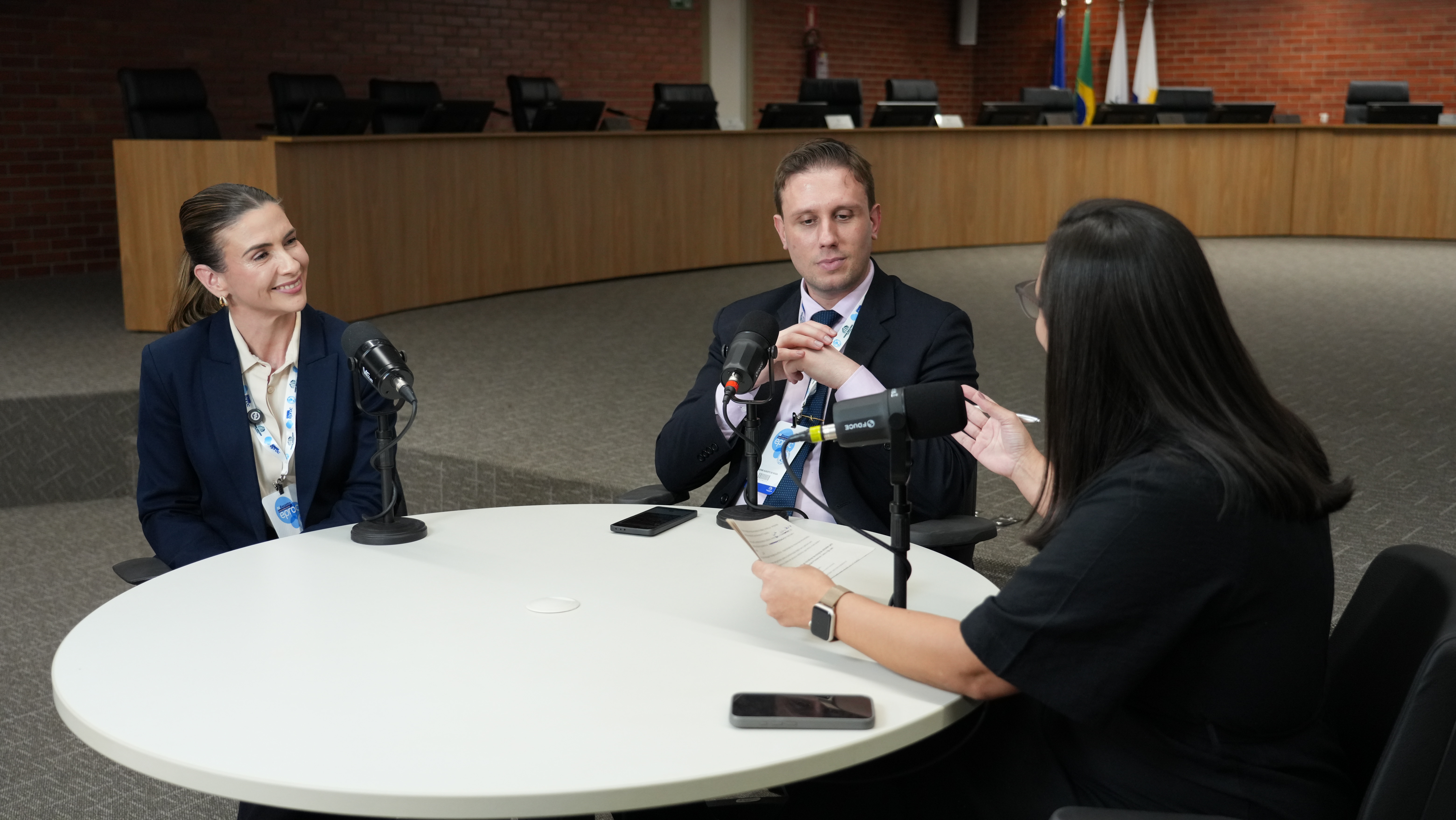 A jornalista Paula Bittencourt conduz a gravação de um episódio da segunda temporada do podcast Conexão JUS, com a participação da servidora Pâmela Pires, do Tribunal de Justiça do Tocantins, e do assessor de Inovação e Tecnologia da Presidência do Tribunal de Justiça do Rio Grande do Sul (TJRS), Guilherme Augusto de Souza. Durante a conversa, os convidados debatem o uso da inteligência artificial no Judiciário e as soluções tecnológicas desenvolvidas no âmbito da comunidade eproc.