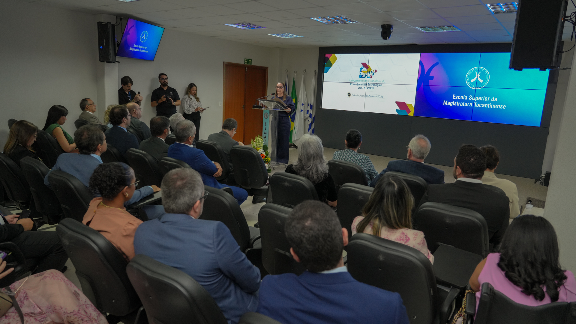 Imagem geral do evento de lançamento dos trabalhos de elaboração do Planejamento Estratégico 2027–2032, realizado em um auditório com a presença de magistrados(as), servidores(as) e gestores(as). Em primeiro plano, o público aparece sentado. Ao fundo, a presidente do TJTO, desembargadora Maysa Vendramini Rosal, faz uso da palavra em um púlpito.de elaboração do Planejamento Estratégico 2027-2032, realizado em um auditório com muitos participantes, que aparecem sentados. Ao fundo, a presidente do TJTO, desembargadora Maysa, fala ao microfone. Ela está em pé, em um pulpito 