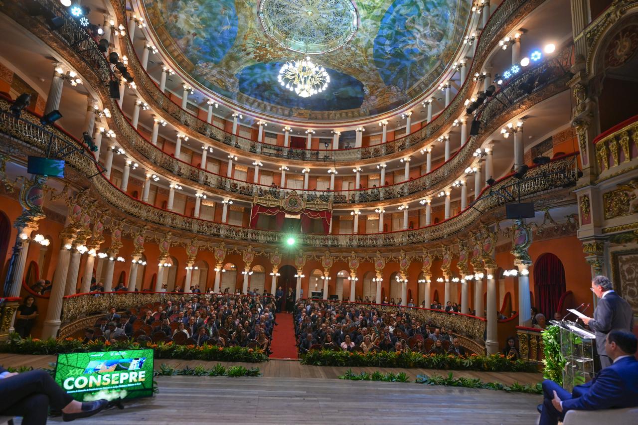 A imagem mostra o público reunido no histórico Teatro Amazonas, durante a solenidade de abertura do XXI Consepre, realizada na noite desta quarta-feira (12/8), em Manaus. No palco, autoridades acompanham a cerimônia, enquanto o telão destaca o XXI Consepre e a arquitetura histórica do teatro compõe o cenário do evento.